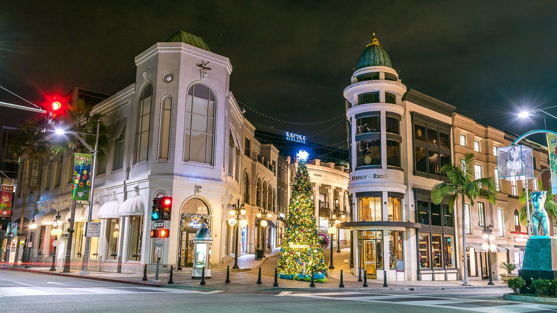 Rodeo Drive at night in Beverly Hills, California, featuring holiday decorations and a Christmas tree, showcasing luxury shopping and festive ambiance.