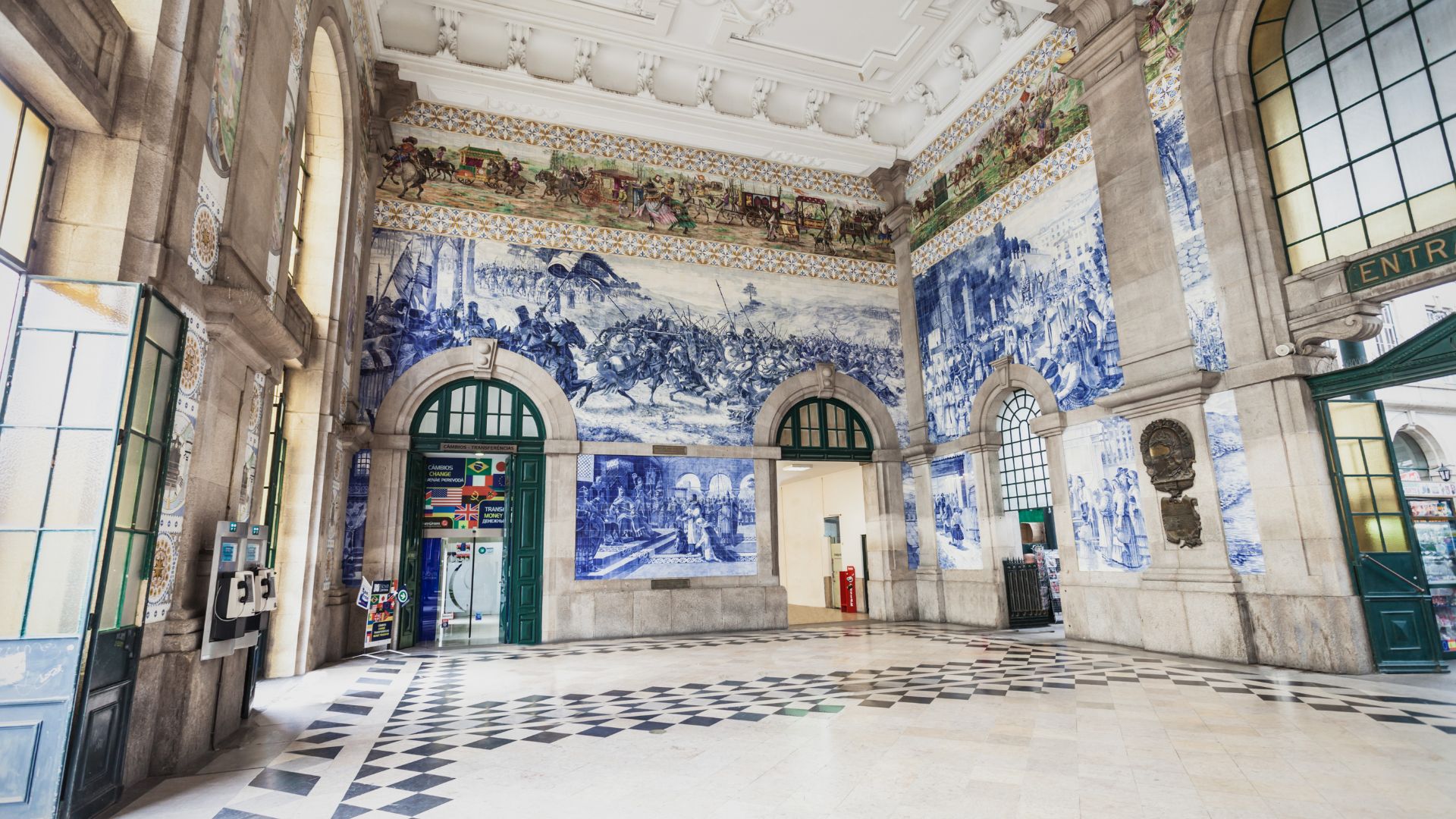 A view of the interior of the São Bento Railway Station in Porto, Portugal, showcasing the elaborate blue and white azulejo tile murals that cover the walls.