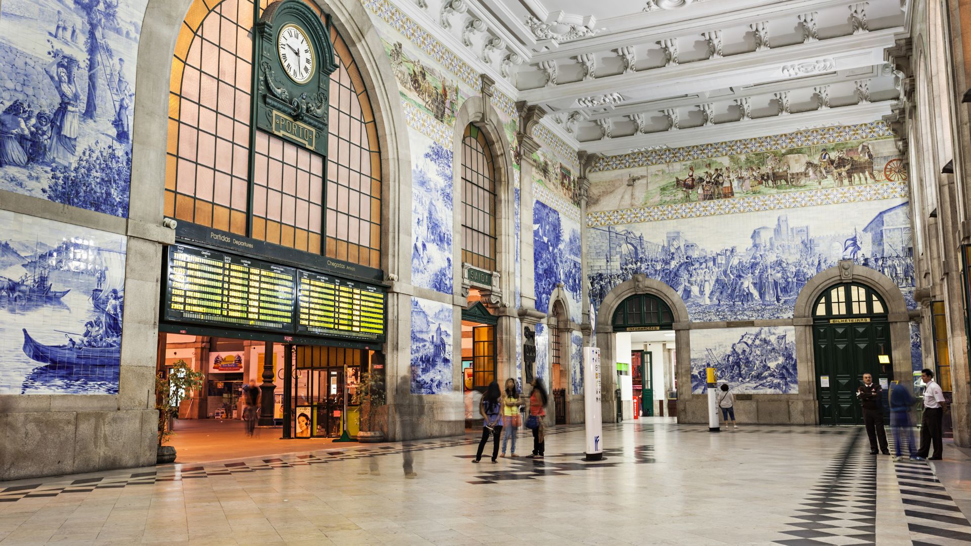 A view of the interior of the São Bento Railway Station in Porto, Portugal, showcasing the elaborate blue and white azulejo tile murals that cover the walls.