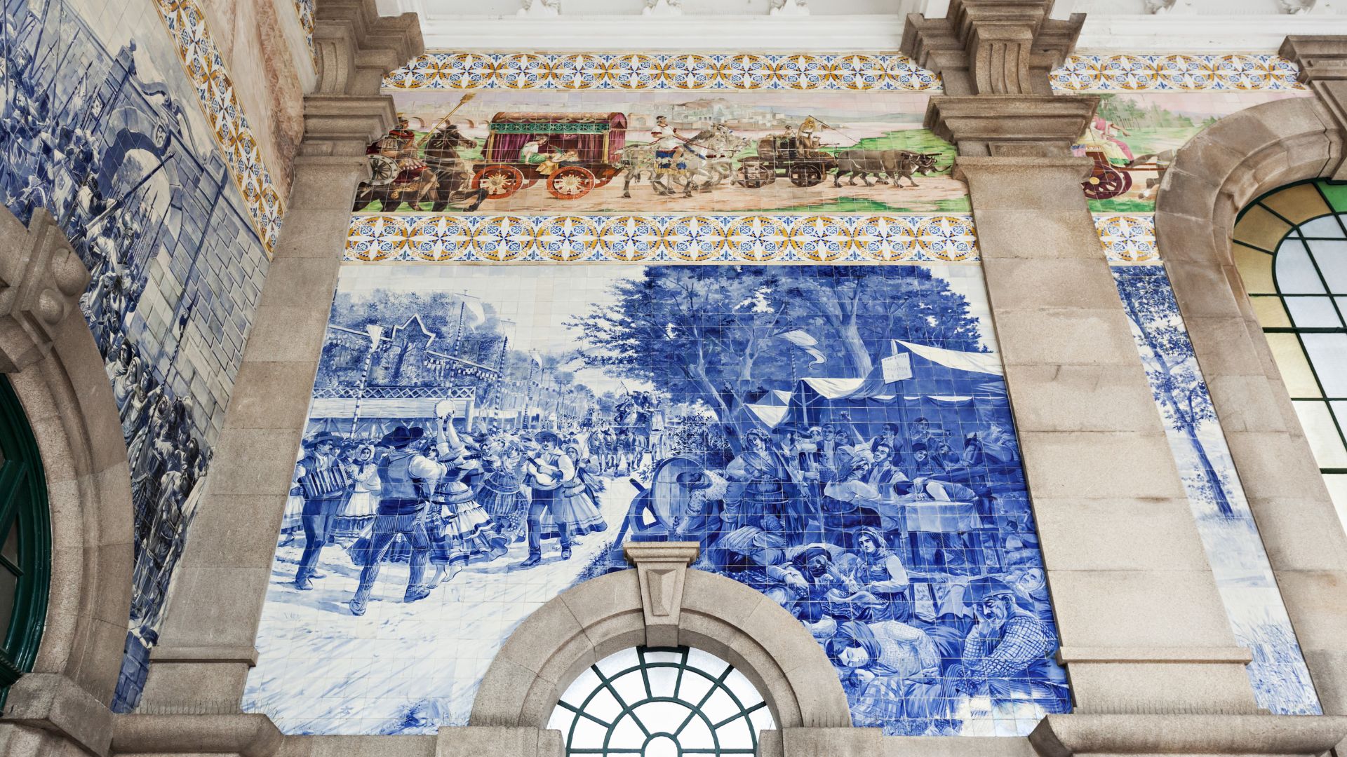 A view of the interior of the São Bento Railway Station in Porto, Portugal, showcasing the elaborate blue and white azulejo tile murals that cover the walls.
