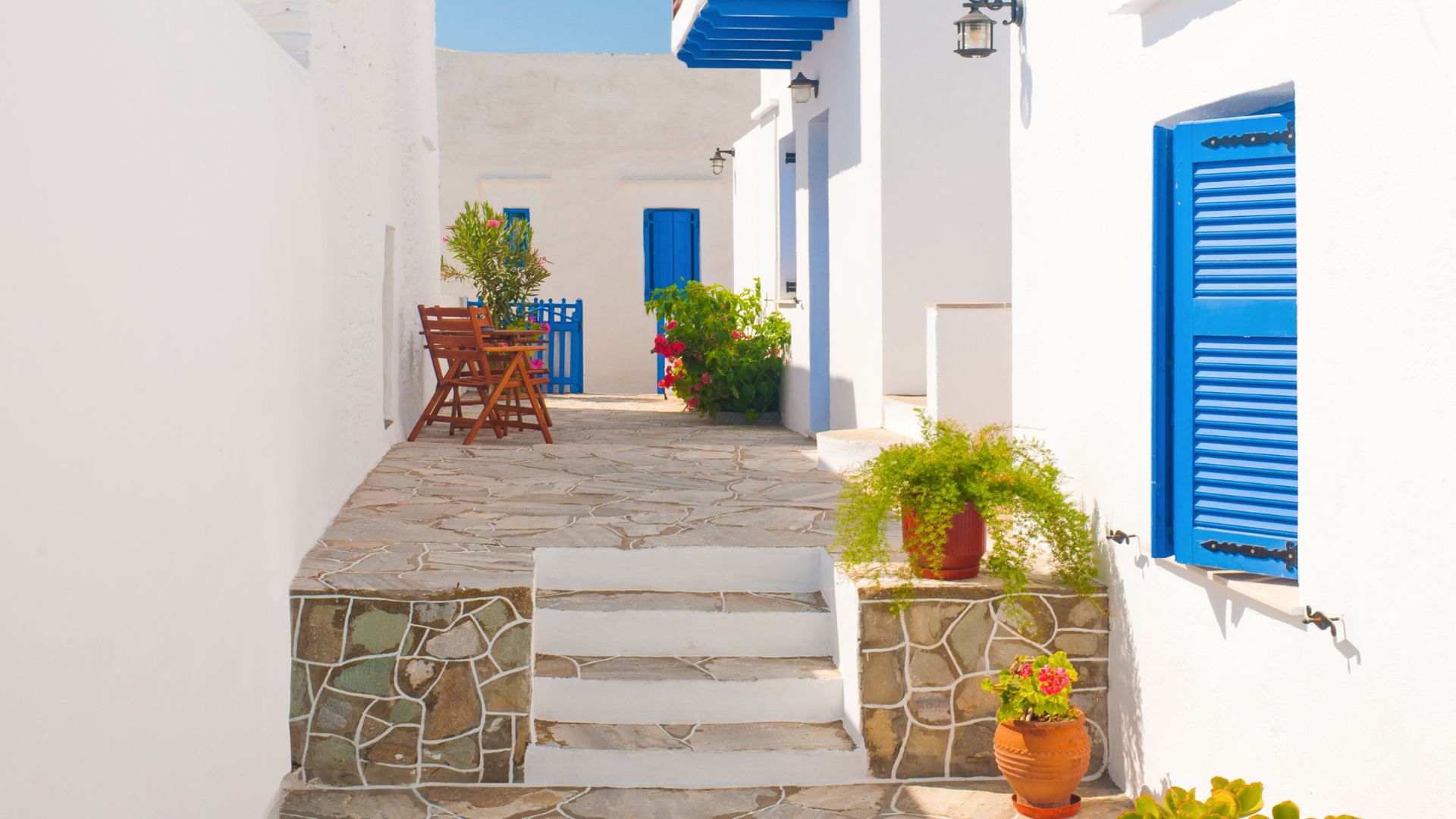 Charming alleyway with whitewashed walls and blue accents in Sifnos, Greece.