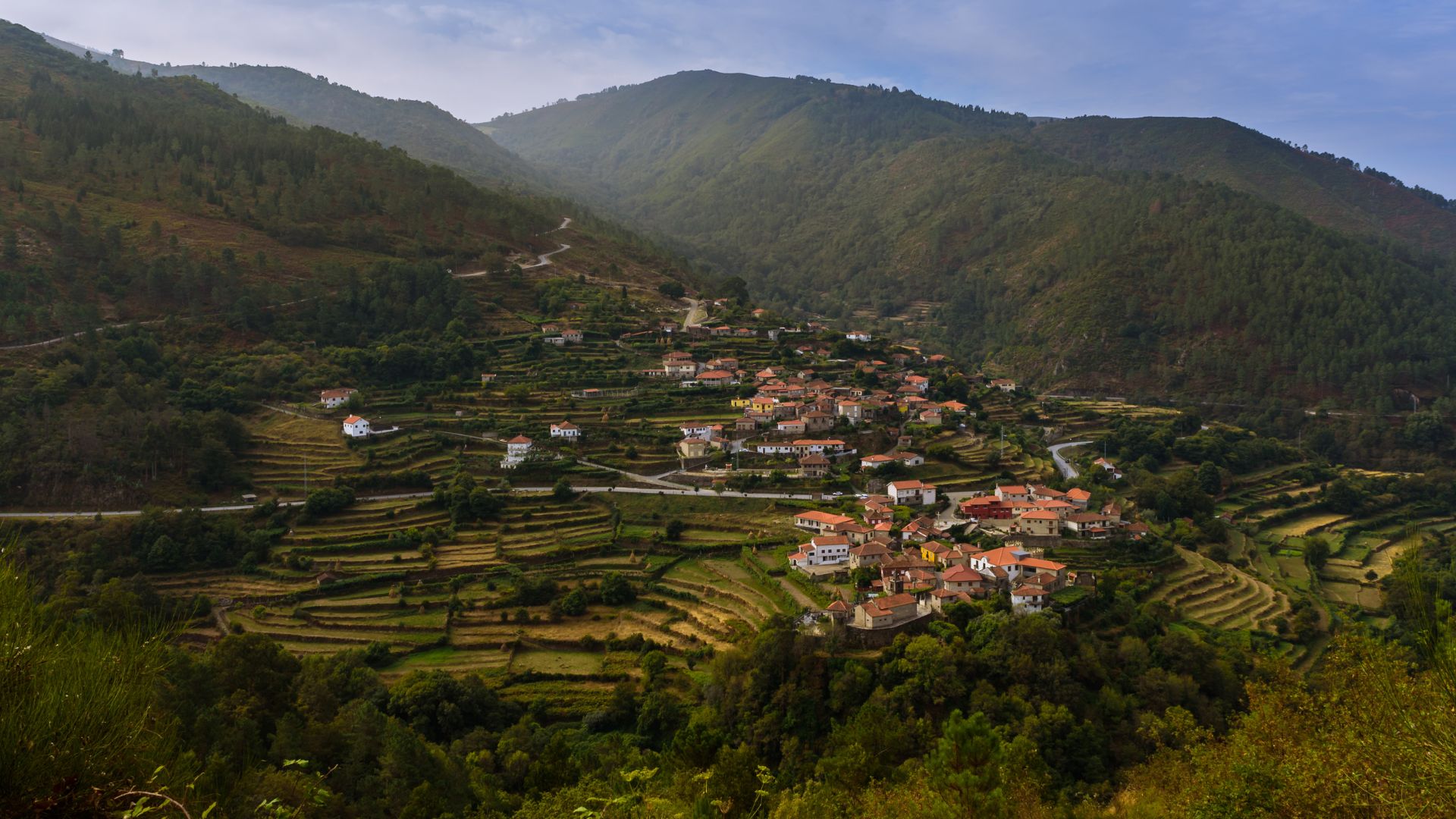 An aerial view of Sistelo village in Portugal, showing terraced hillsides and traditional houses nestled in a lush green valley.