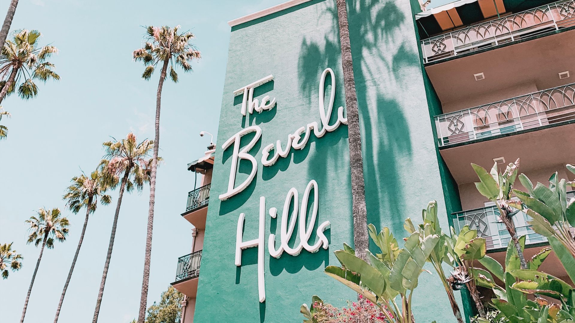 The Beverly Hills Hotel with palm trees in Beverly Hills, California. The hotel's iconic pink facade and lush surroundings are a popular destination.