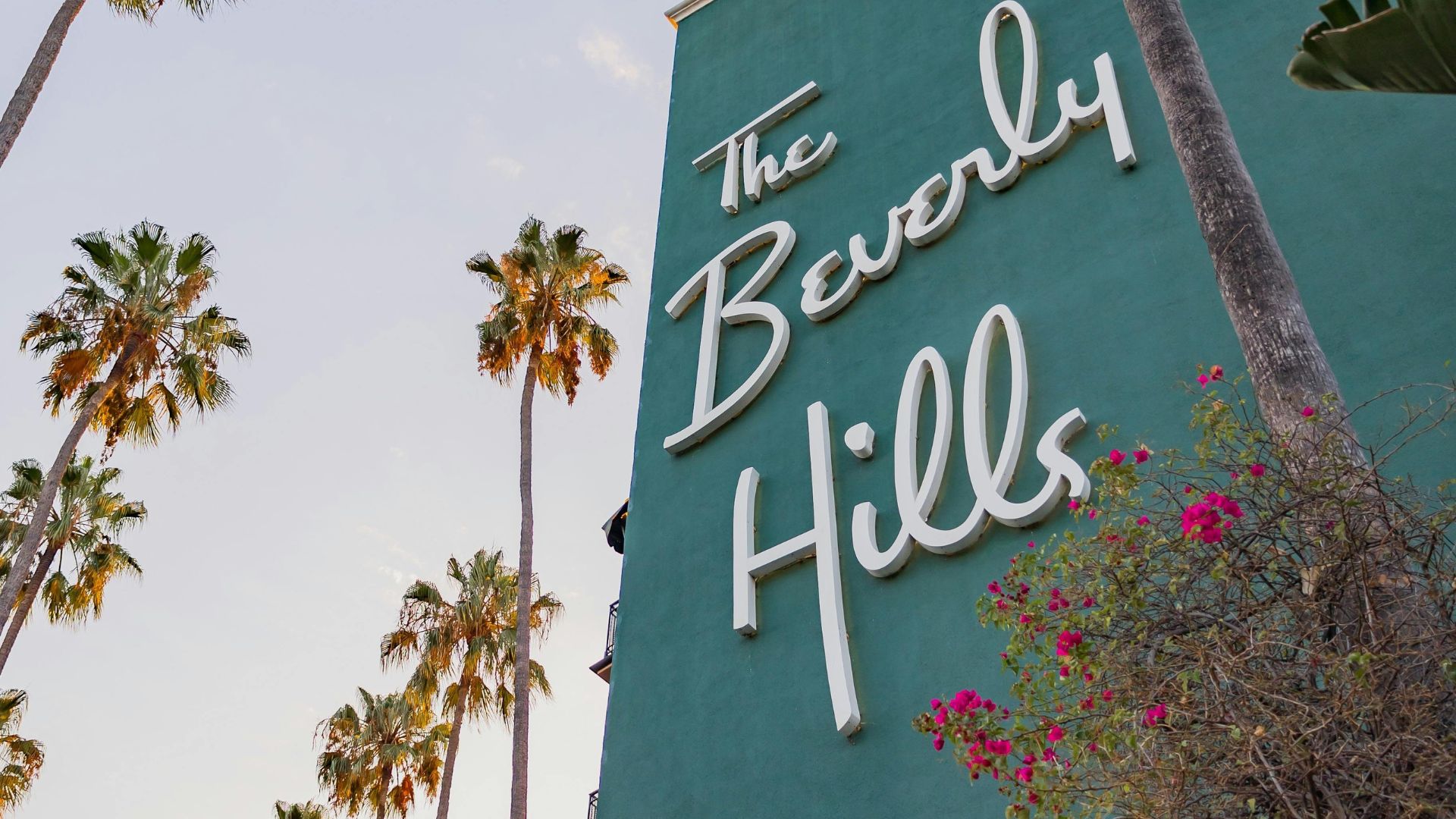 The Beverly Hills Hotel with palm trees in Beverly Hills, California. The hotel's iconic pink facade and lush surroundings are a popular destination.