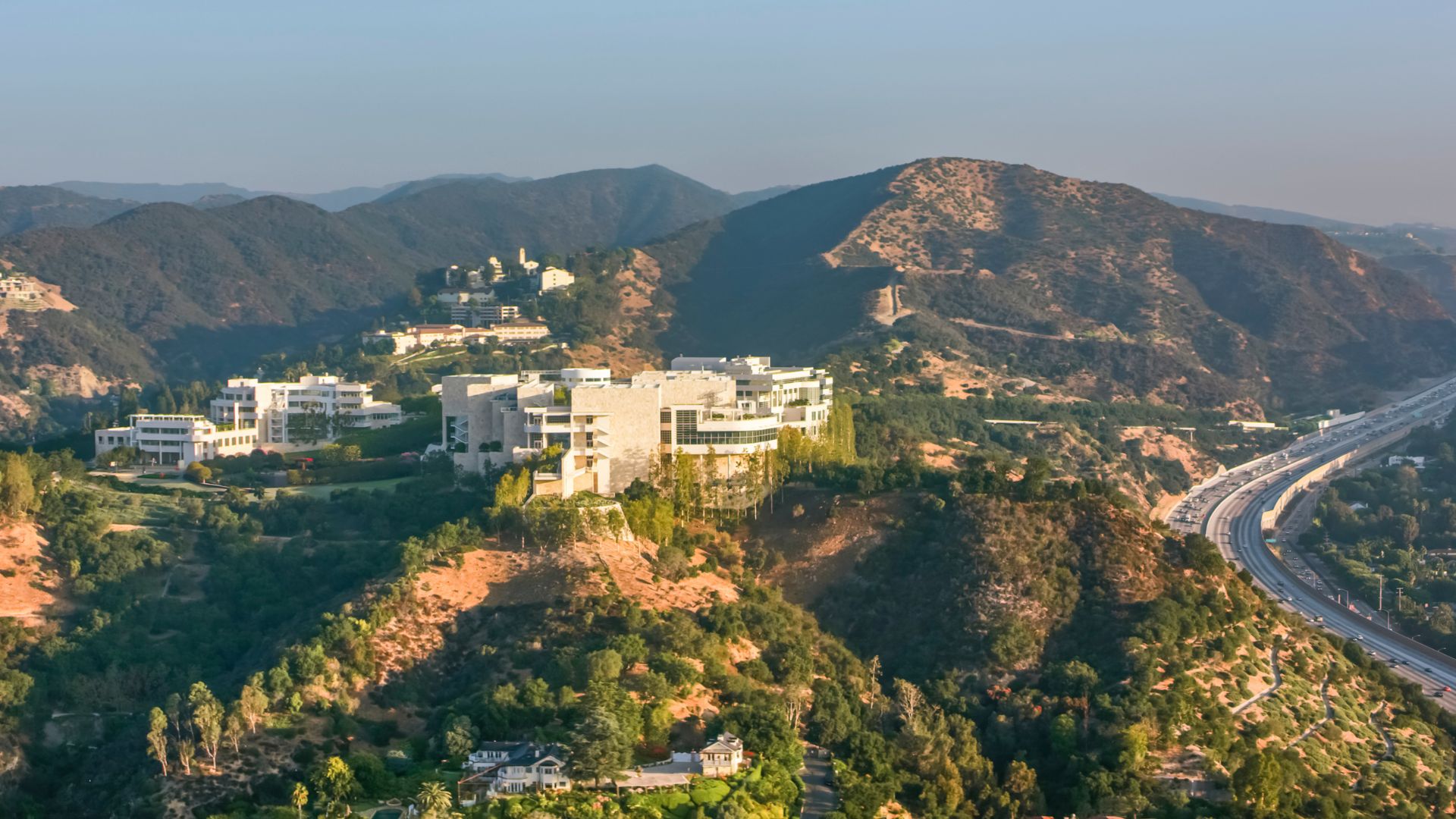 Aerial view of the Getty Center in Los Angeles, California, showcasing its modern architecture nestled in the hills with surrounding mountains and greenery.