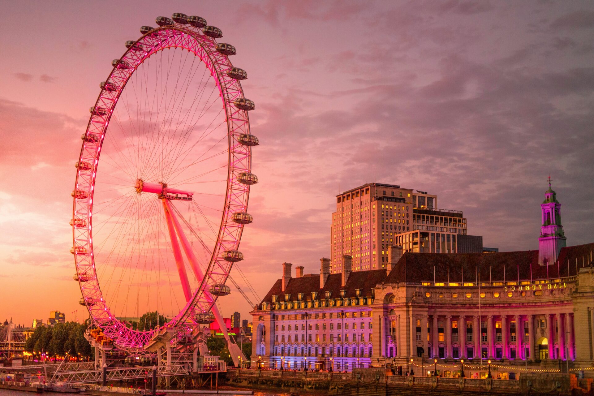 The London Eye at sunset, glowing in the warm orange and pink hues of the sky