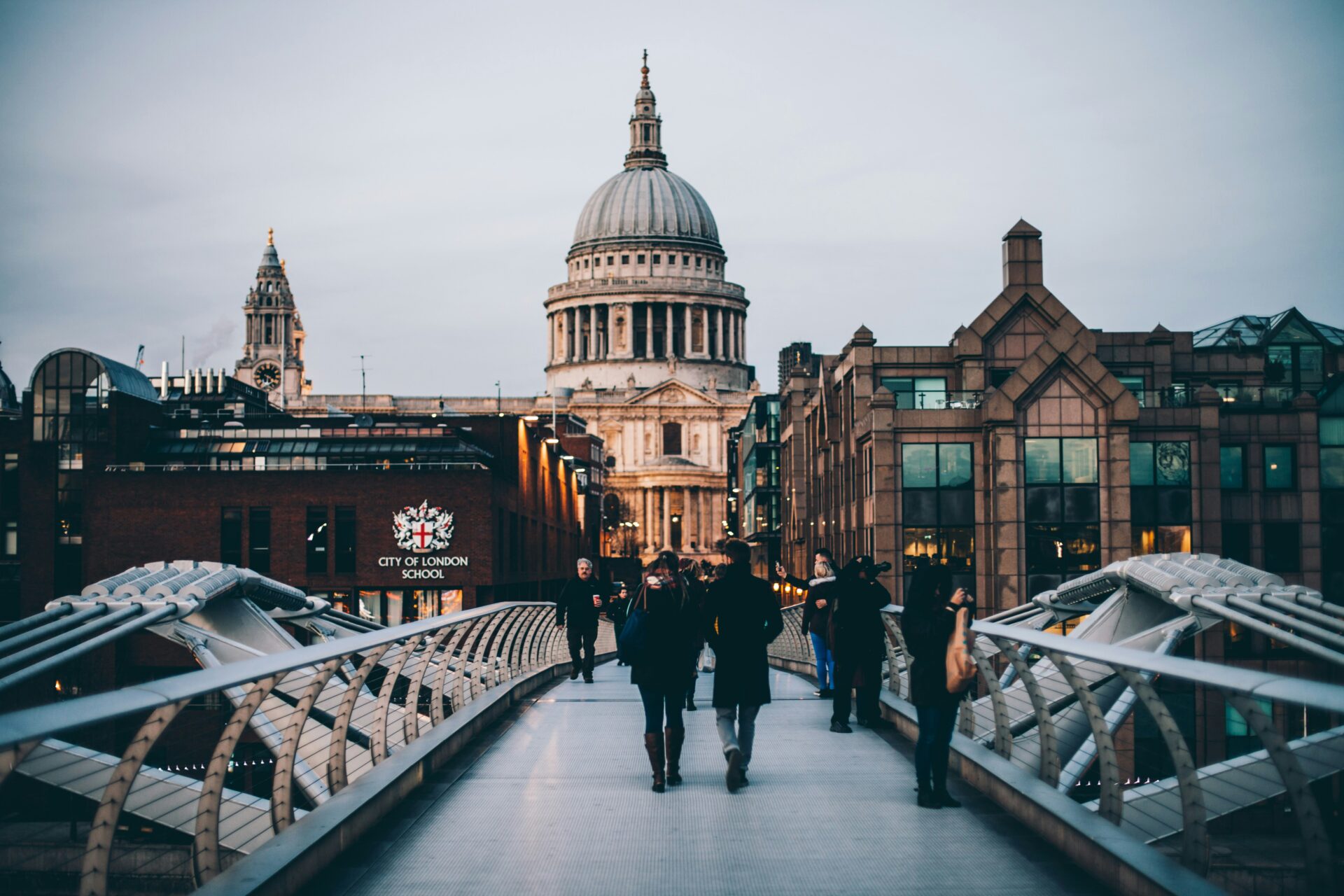 The Millennium Bridge in London, connecting St. Paul's Cathedral to Tate Modern, with pedestrians crossing over the River Thames.