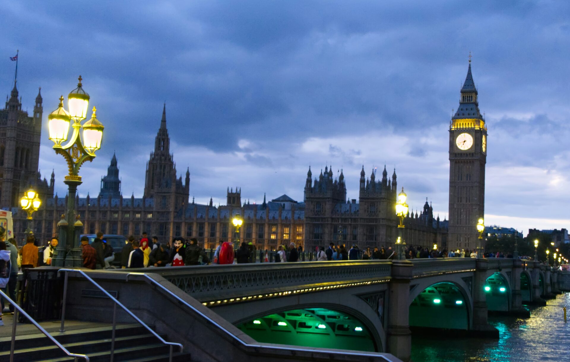 Visitors standing near the Houses of Parliament by the River Thames.
