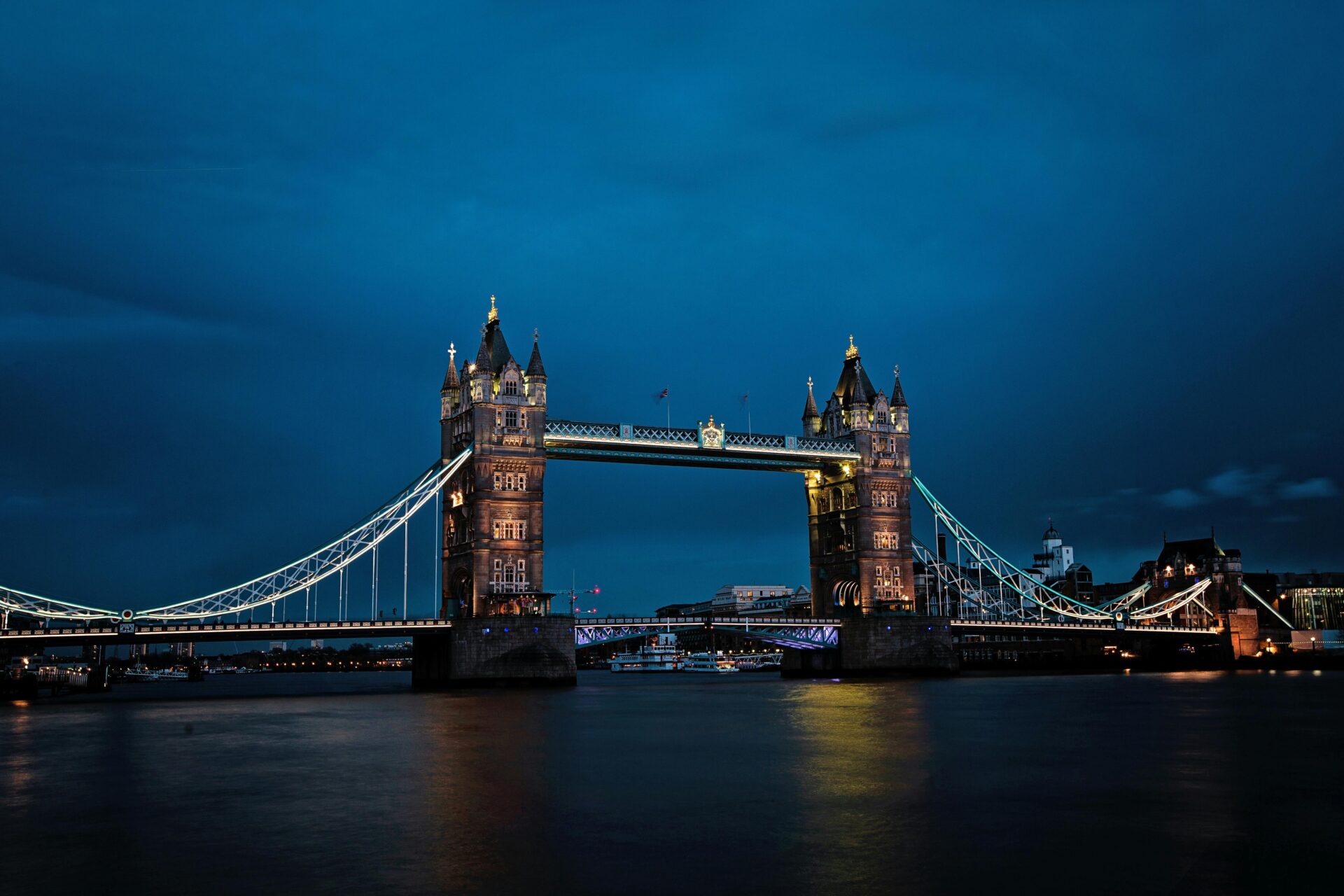 Tower Bridge illuminated at night with golden and blue lights glowing against the dark sky