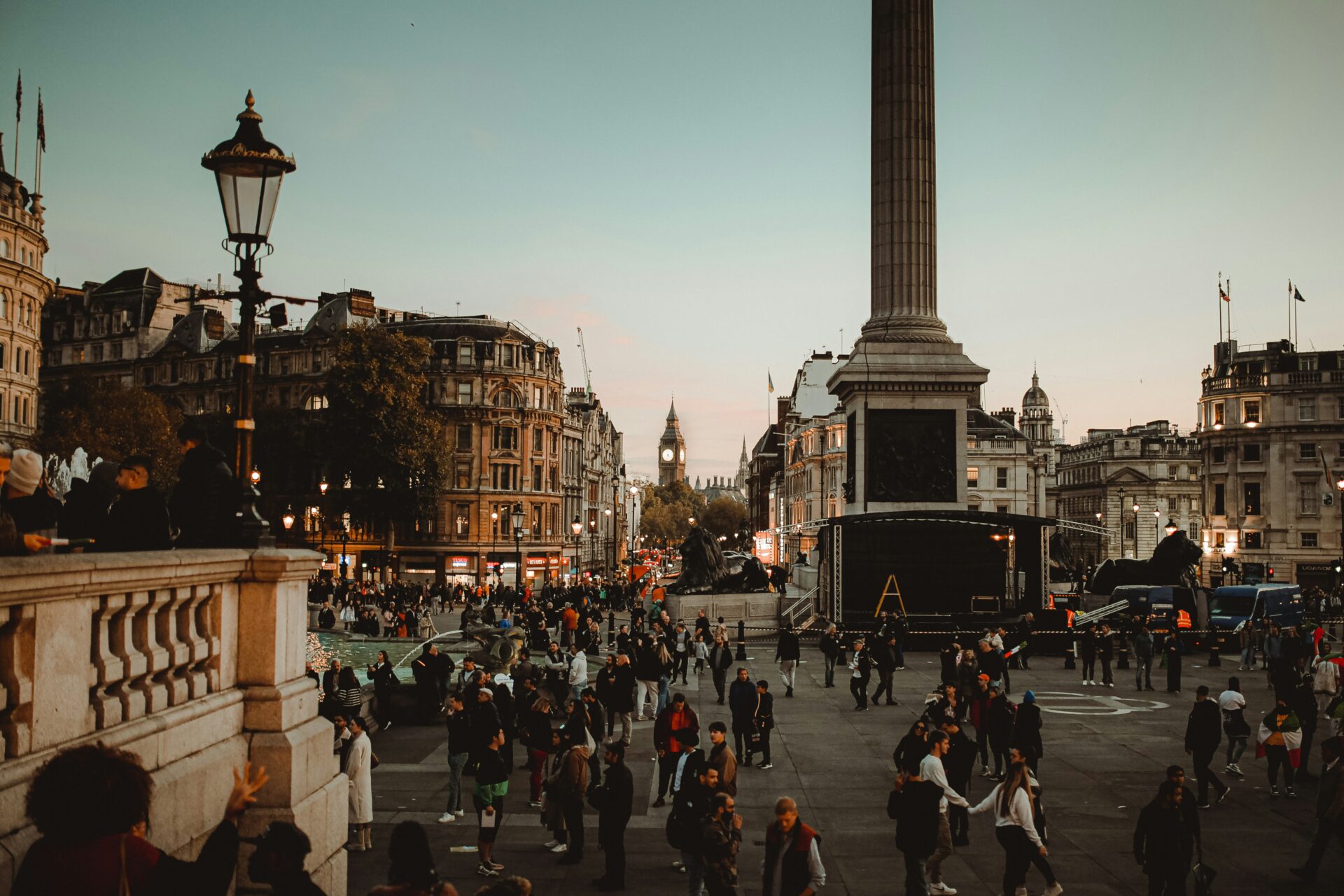 Trafalgar Square filled with people under warm sunset light