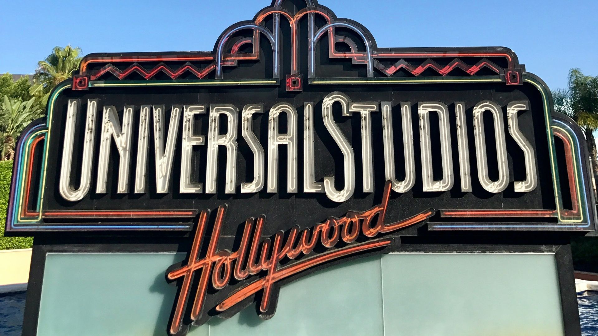 Universal Studios Hollywood entrance sign, a popular tourist destination in Los Angeles, California, with a retro-style sign surrounded by a pool of water.