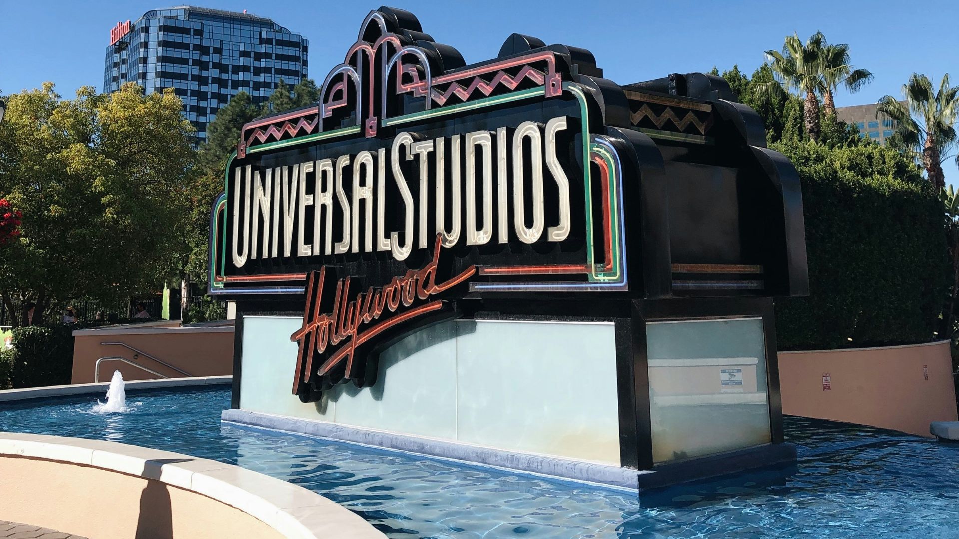 Universal Studios Hollywood entrance sign, a popular tourist destination in Los Angeles, California, with a retro-style sign surrounded by a pool of water.