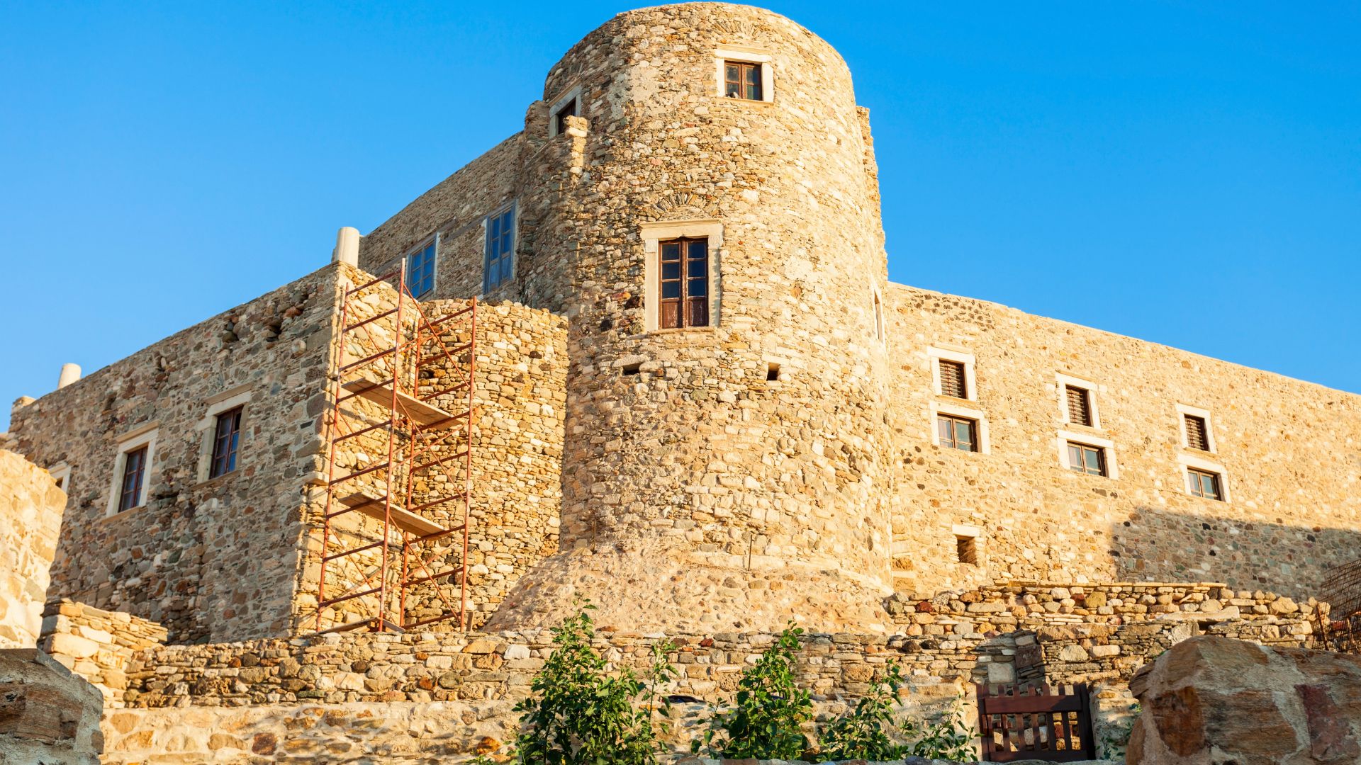 A medieval stone castle with a round tower, located in Naxos, Greece.
