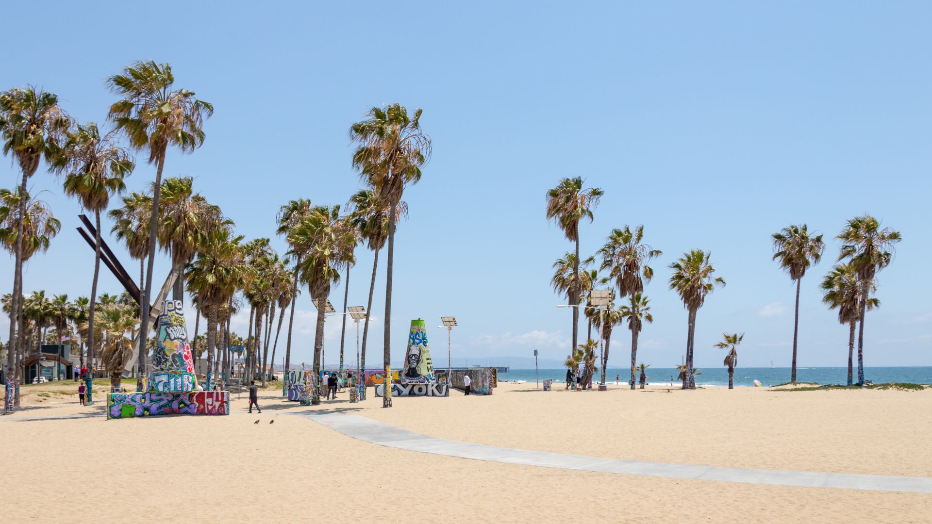 Panoramic view of Venice Beach in Southern California, showcasing palm trees, sandy beach, and the iconic Ocean Front Walk.