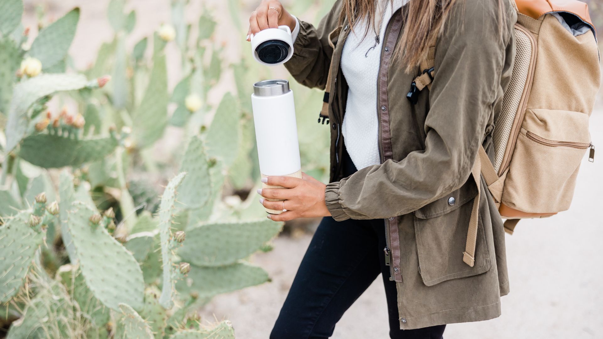 A woman wearing jacket, have a back pack, and holding her tumbler