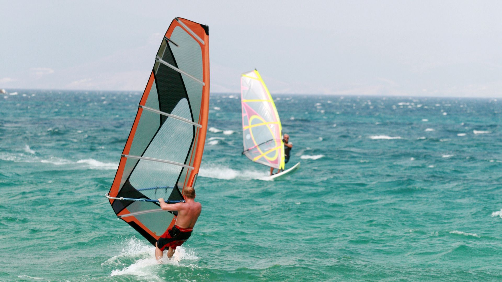 Two wind surfer wind surfing at the sea.
