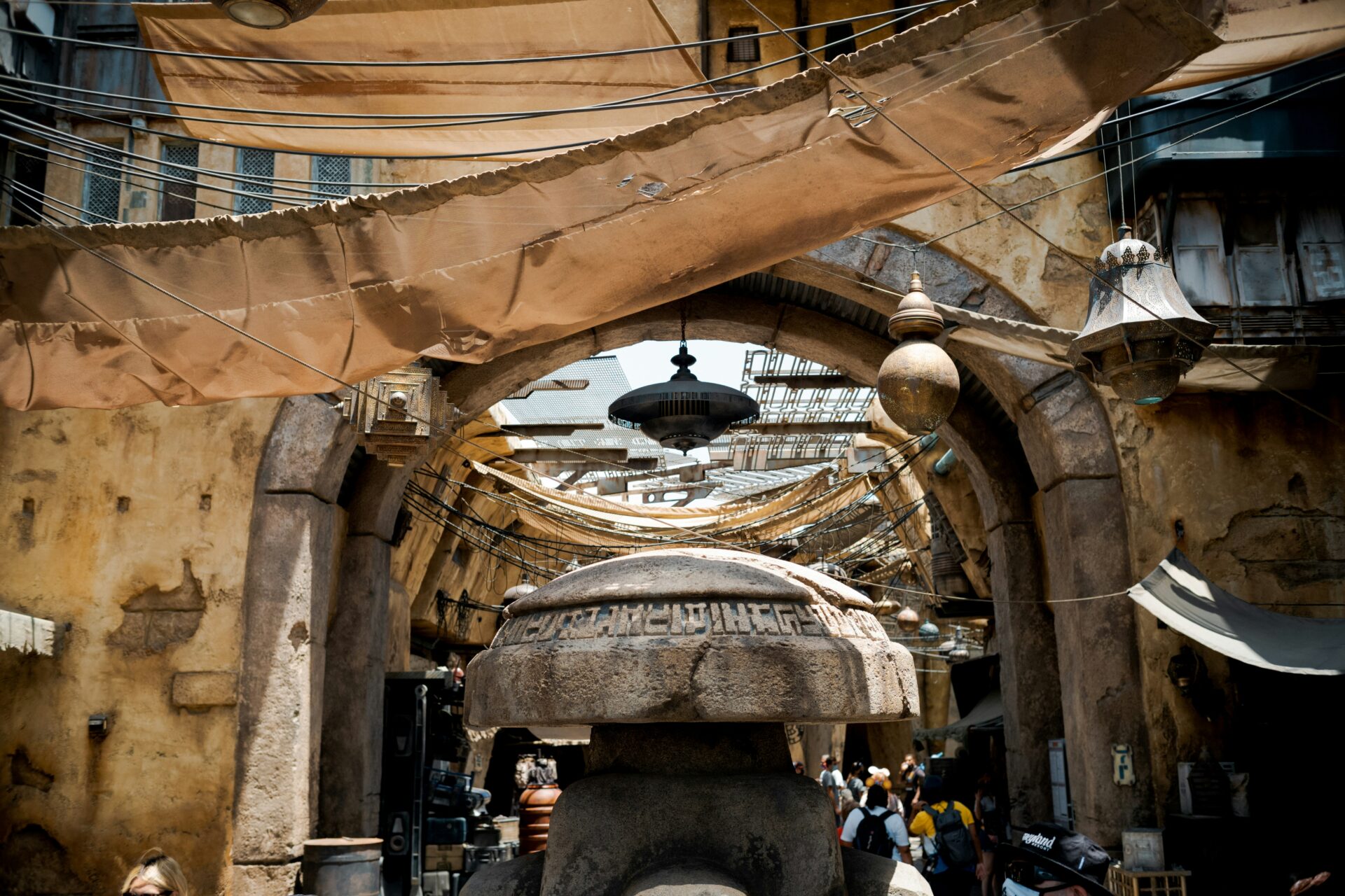 Star Wars Galaxy's Edge Disneyland Park Anaheim entrance archway with overhead tarps, lanterns, and crowds, capturing the immersive atmosphere of Batuu's Black Spire Outpost.