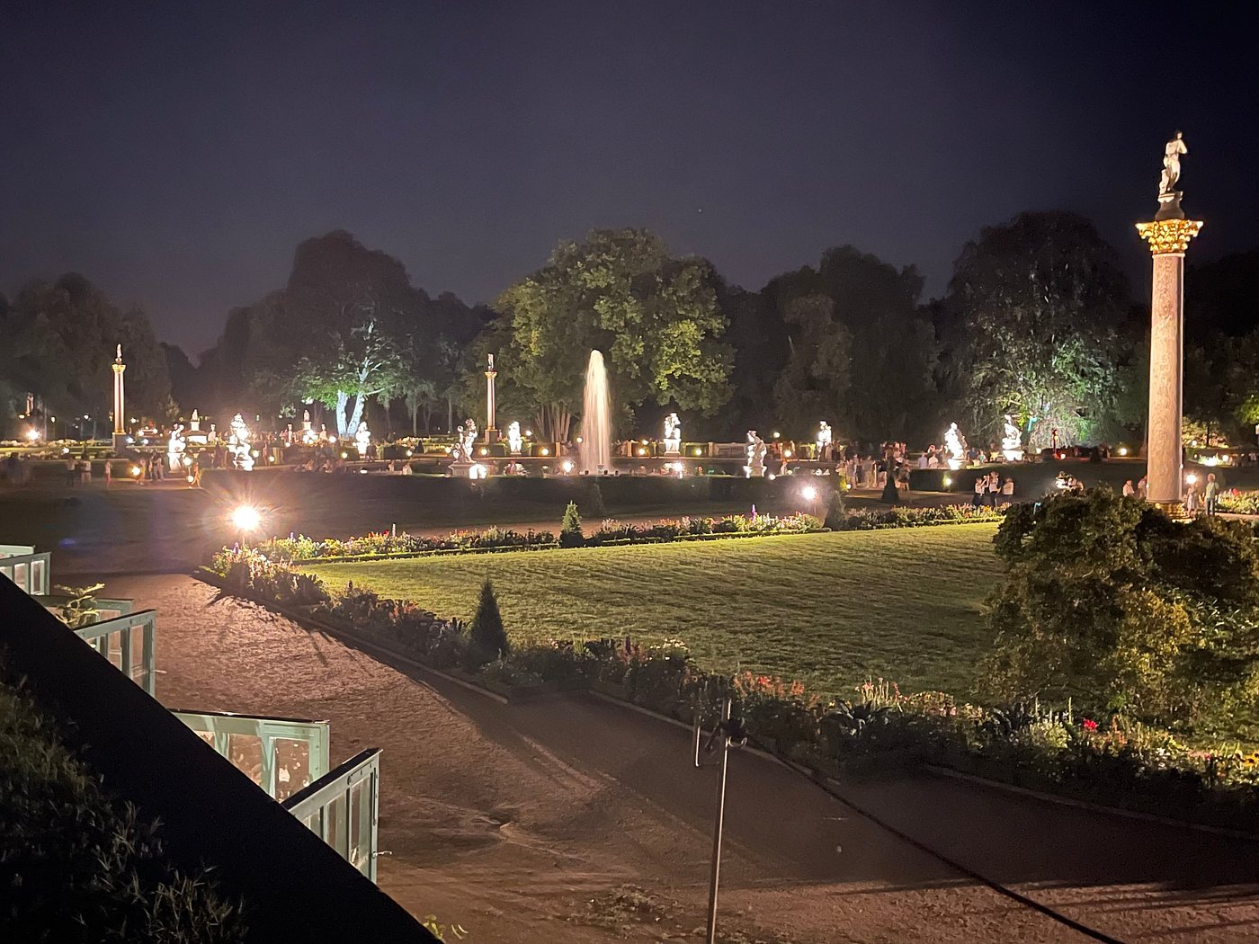 Sanssouci Palace gardens at night with softly lit pathways and shadowy statues among the hedges