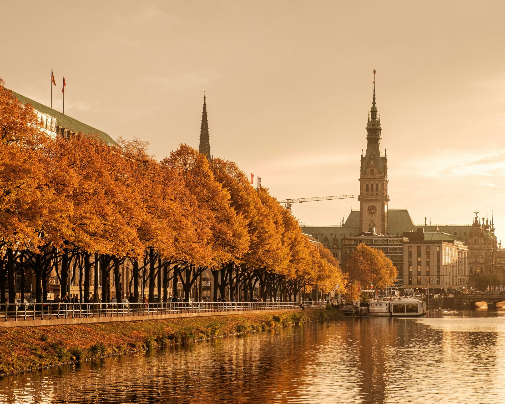 Autumn view of Alster Lake with golden leaves on the trees and reflections of fall colors shimmering on the water.