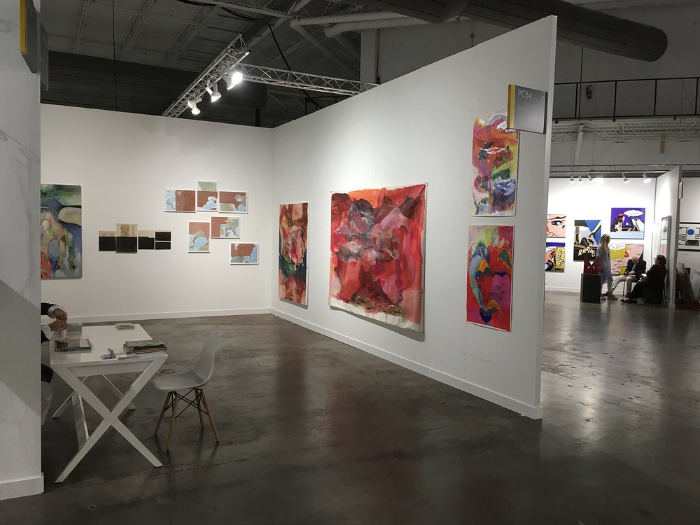 Modern art fair interior with spotlights illuminating artworks at Art Basel Miami.