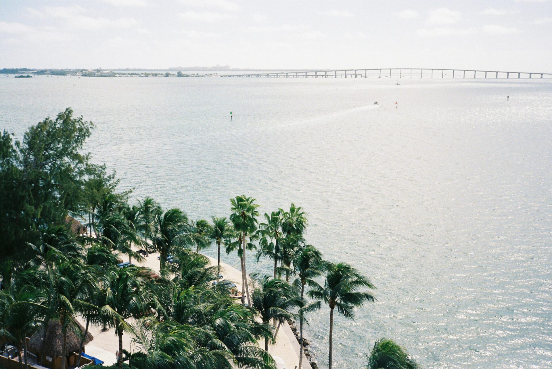Scenic aerial shot of Biscayne Bay showing boats on the water, lush green keys, and bridges connecting the mainland to barrier islands.