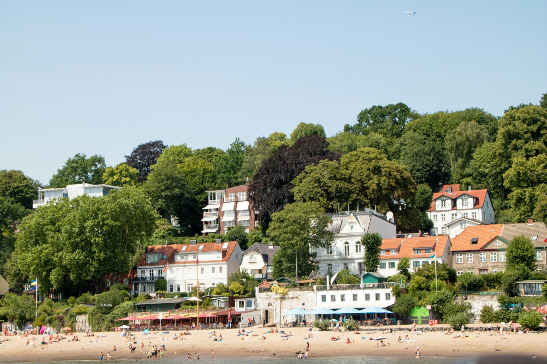 View from above Blankenese village, showing terraced homes nestled in lush trees leading to the waterfront.
