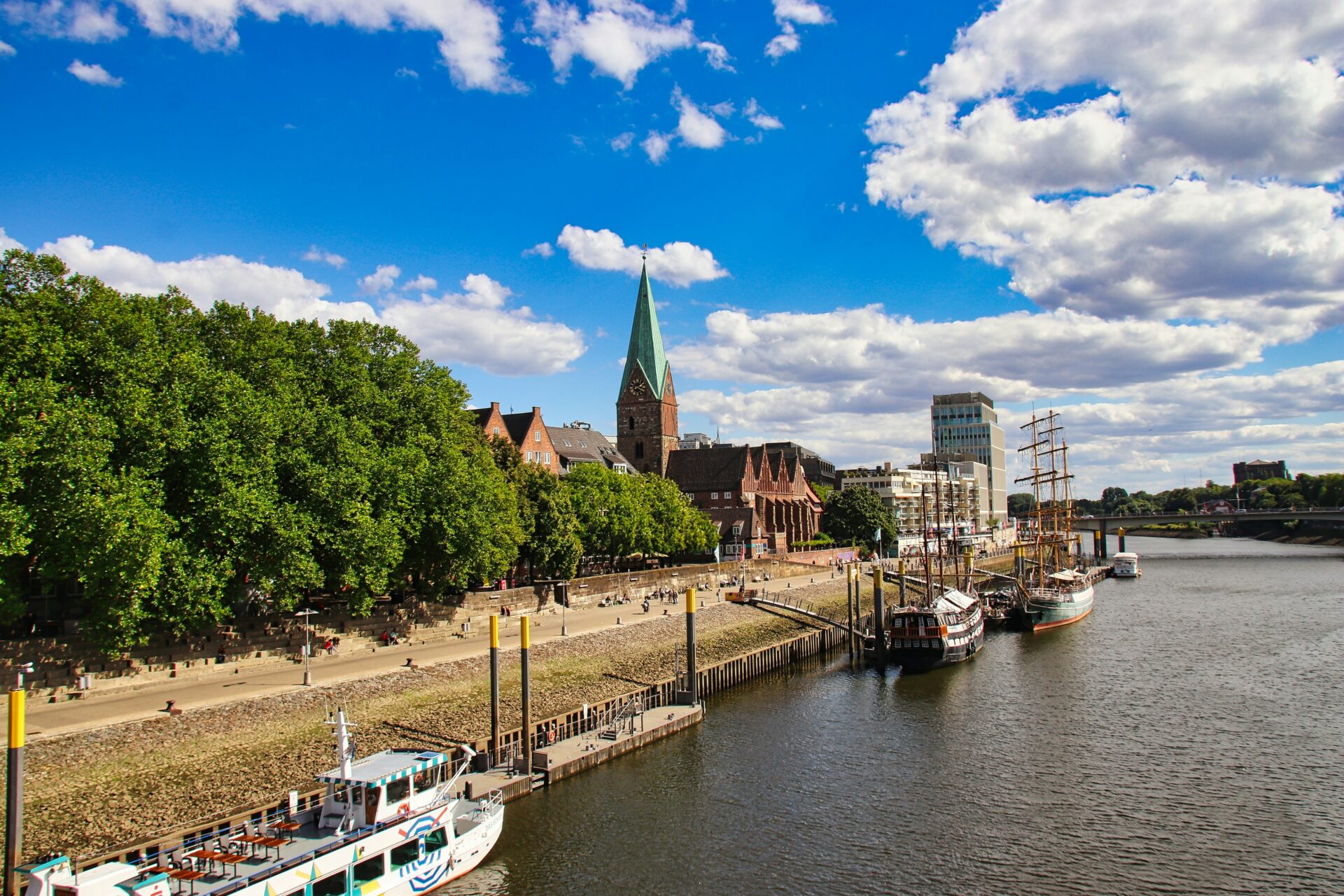 Weser River in Bremen with green trees and boats on a bright summer day