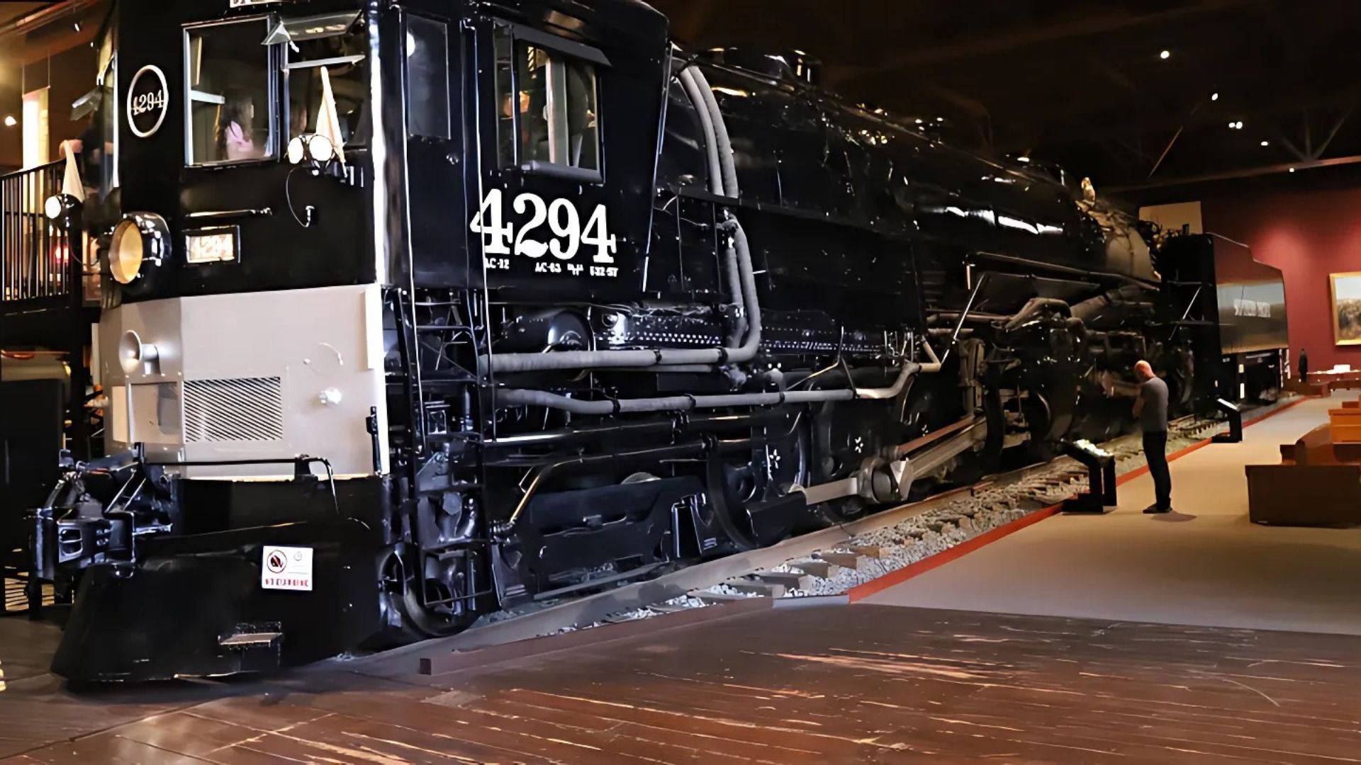 A large, black Southern Pacific 4294 "Cab Forward" steam locomotive on display in the California State Railroad Museum in Sacramento, with a person standing near it.