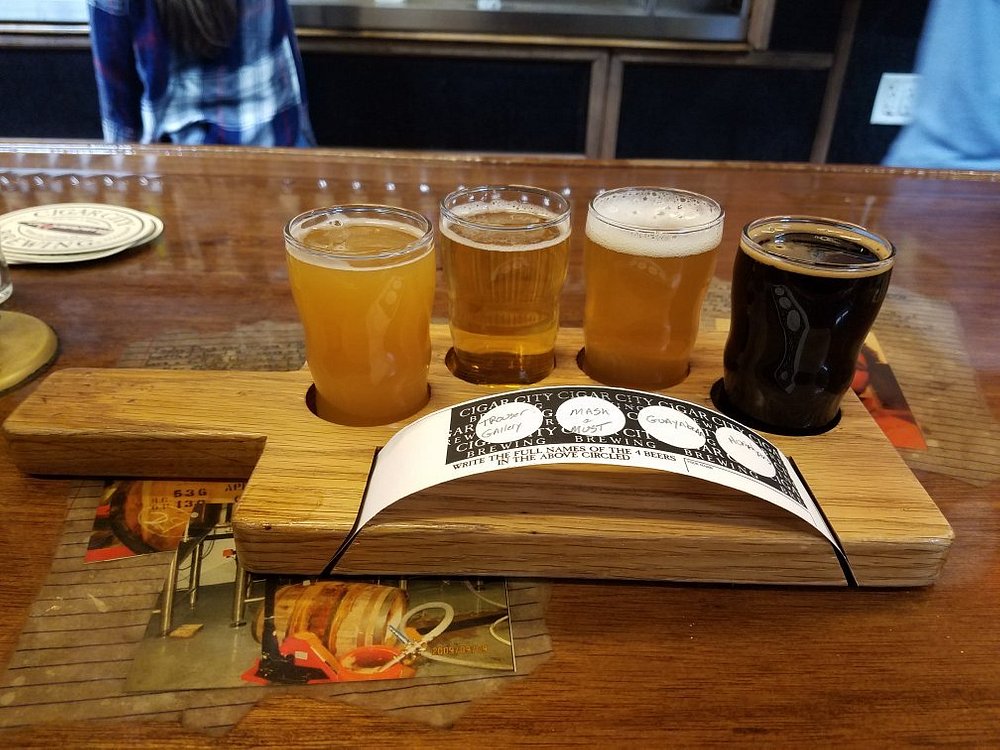 A glass of craft beer served on a rustic wooden tray at Cigar City Brewing in Tampa