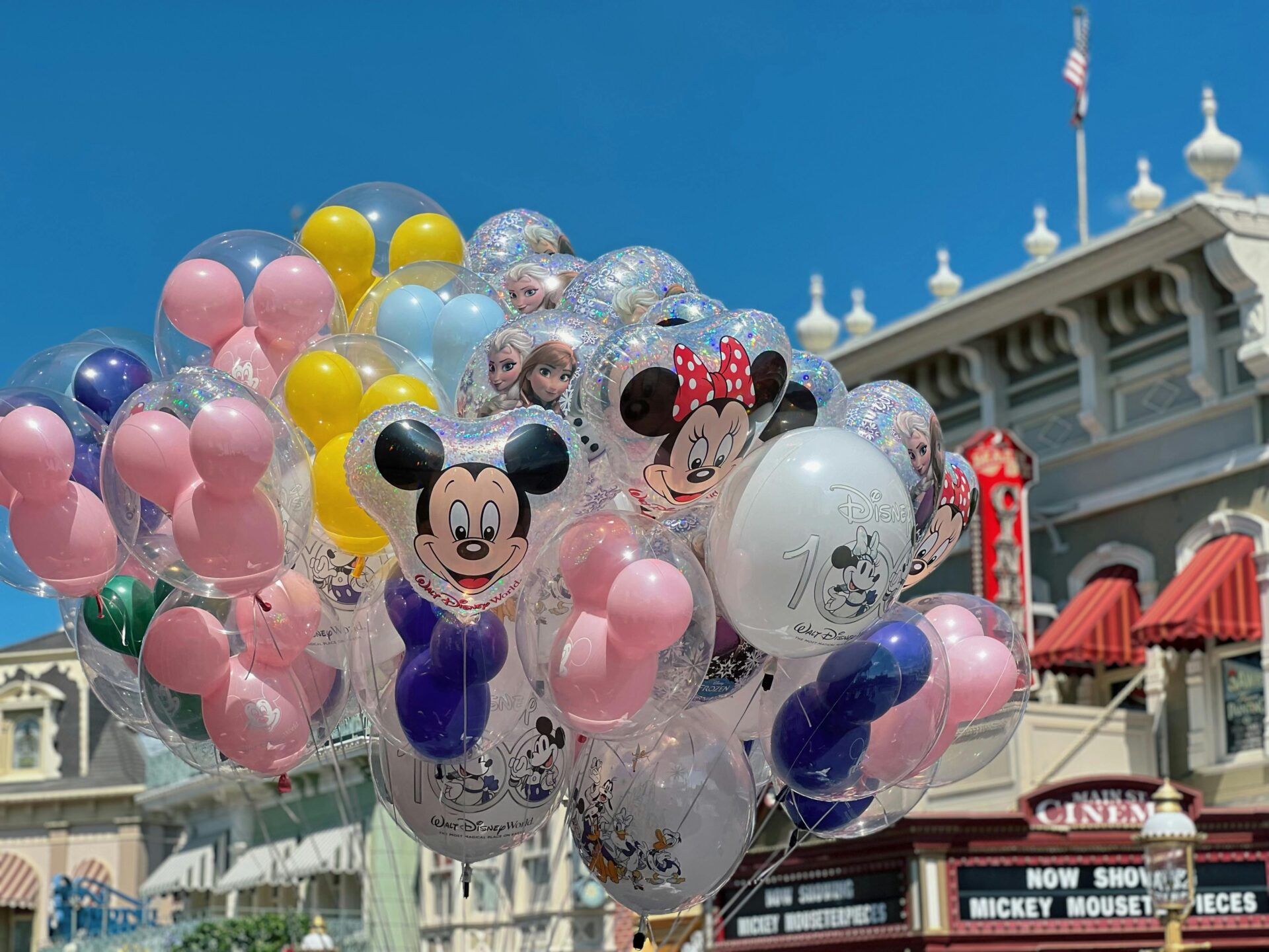 A cluster of vibrant, colorful balloons floating in the air at a Disney theme park