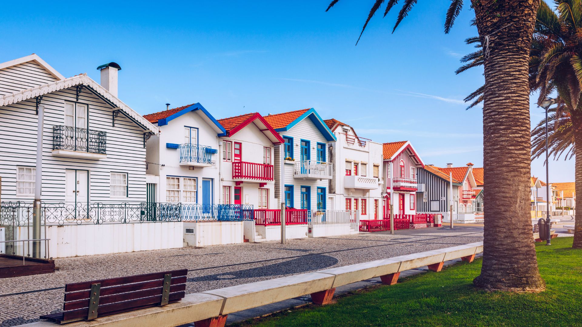 The image showcases the iconic, colorful striped houses, known as "palheiros," of Costa Nova, a charming seaside village in Portugal known for its picturesque architecture and proximity to a beautiful sandy beach.