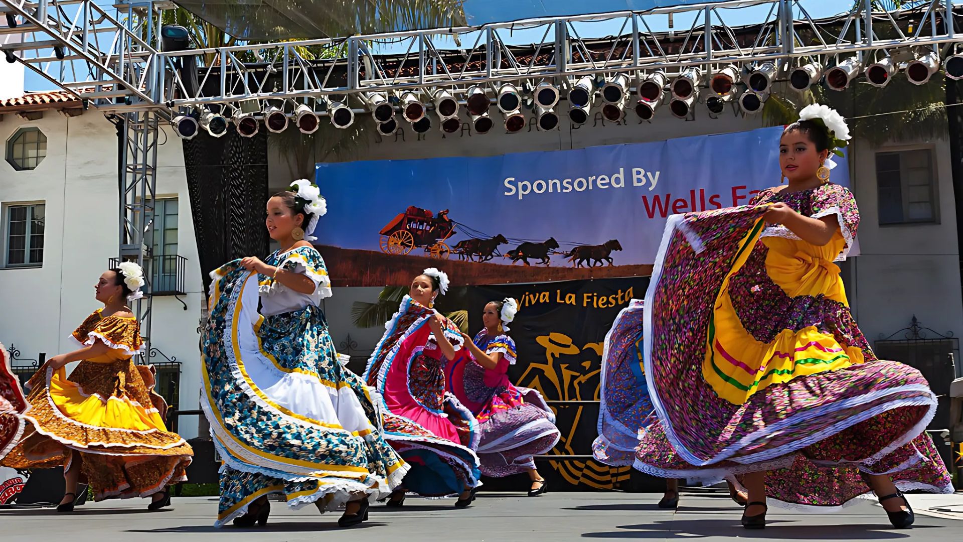 Girls dancing on stage wearing colorful dresses for Folklórico during Old Spanish Days Fiesta in Santa Barbara, California.
