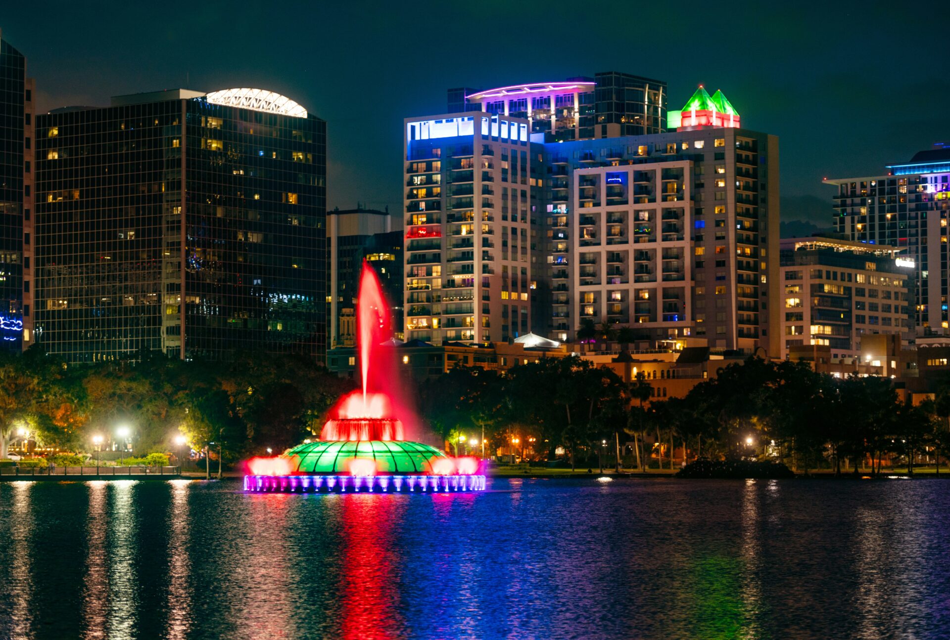 Lake Eola Park fountain illuminated in vibrant colors at night during Fourth of July celebrations