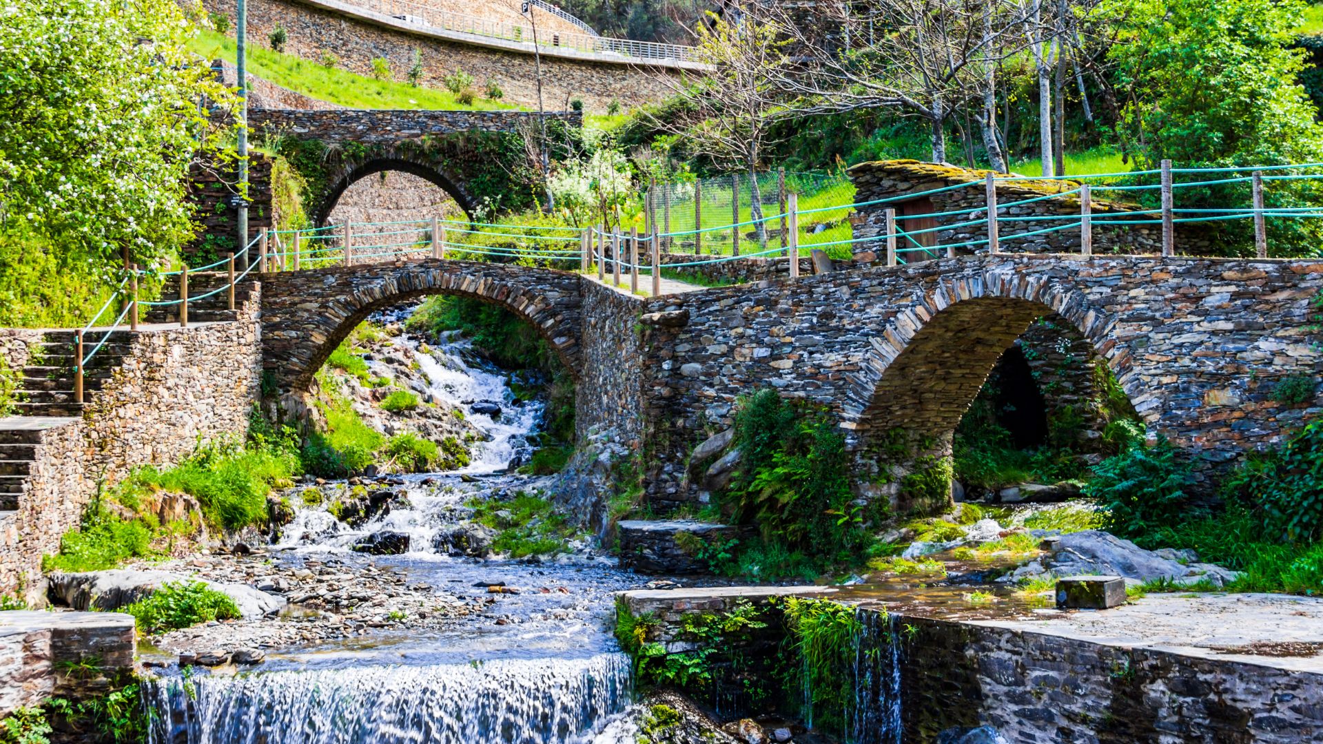 Stone bridges arch over a cascading river in a lush, green valley, showcasing the picturesque Foz d'Égua in Portugal.