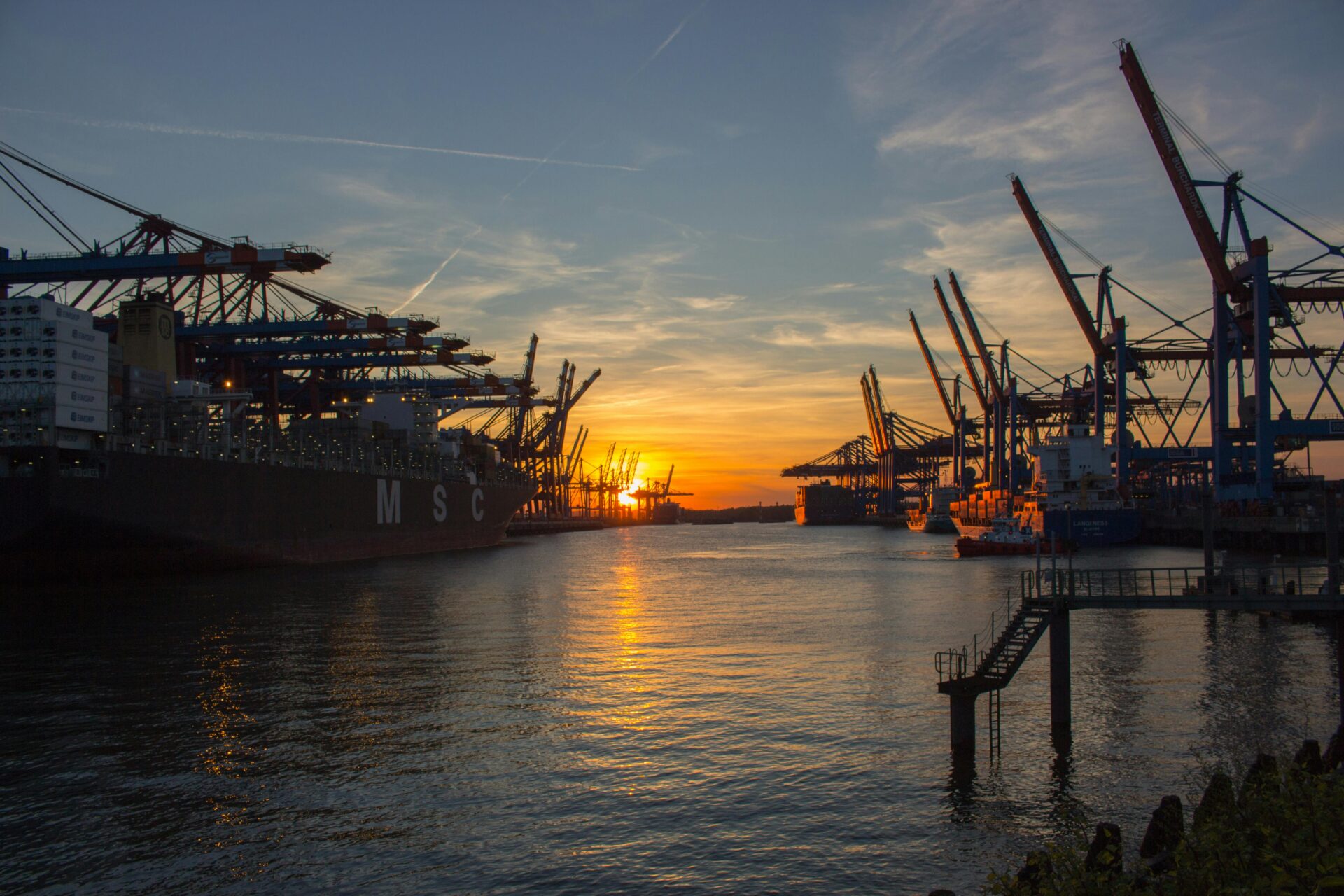 Golden hour view of ships docked at Hamburg Port as the sun sets.