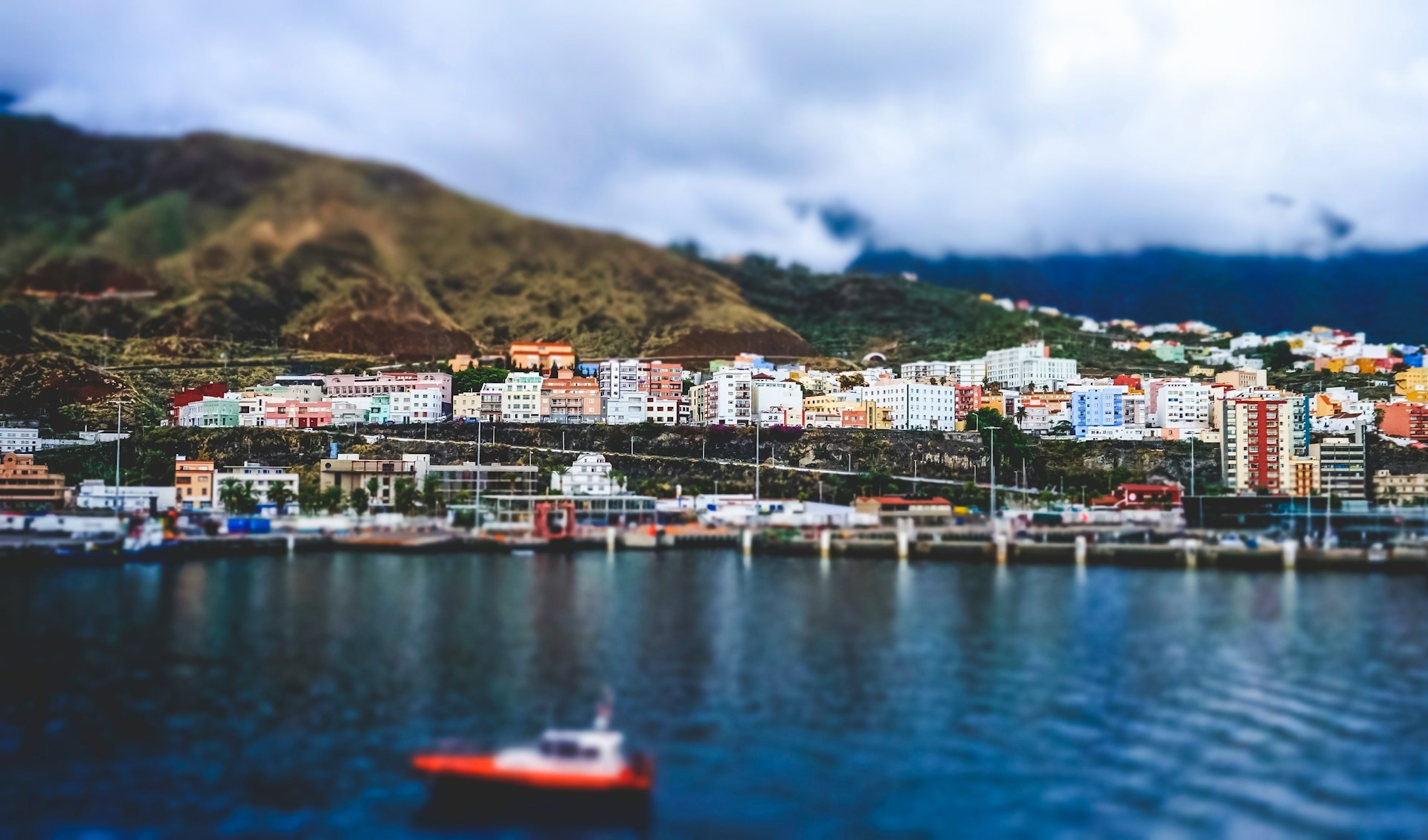 Pastel-colored homes nestled into the hillside, framed by palm trees and overlooking the deep blue ocean