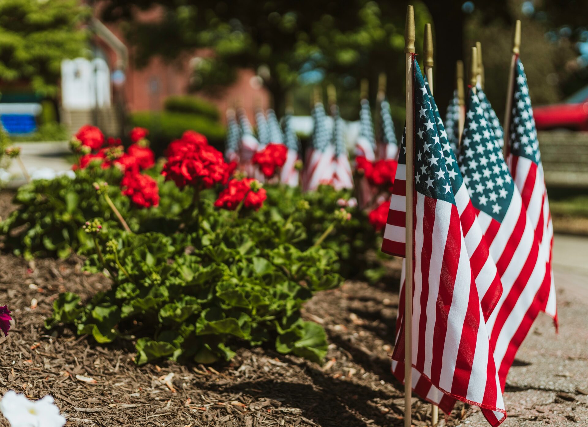 Memorial Day ceremony in Orlando with American flags and flowers placed at a veteran's memorial, honoring fallen soldiers.