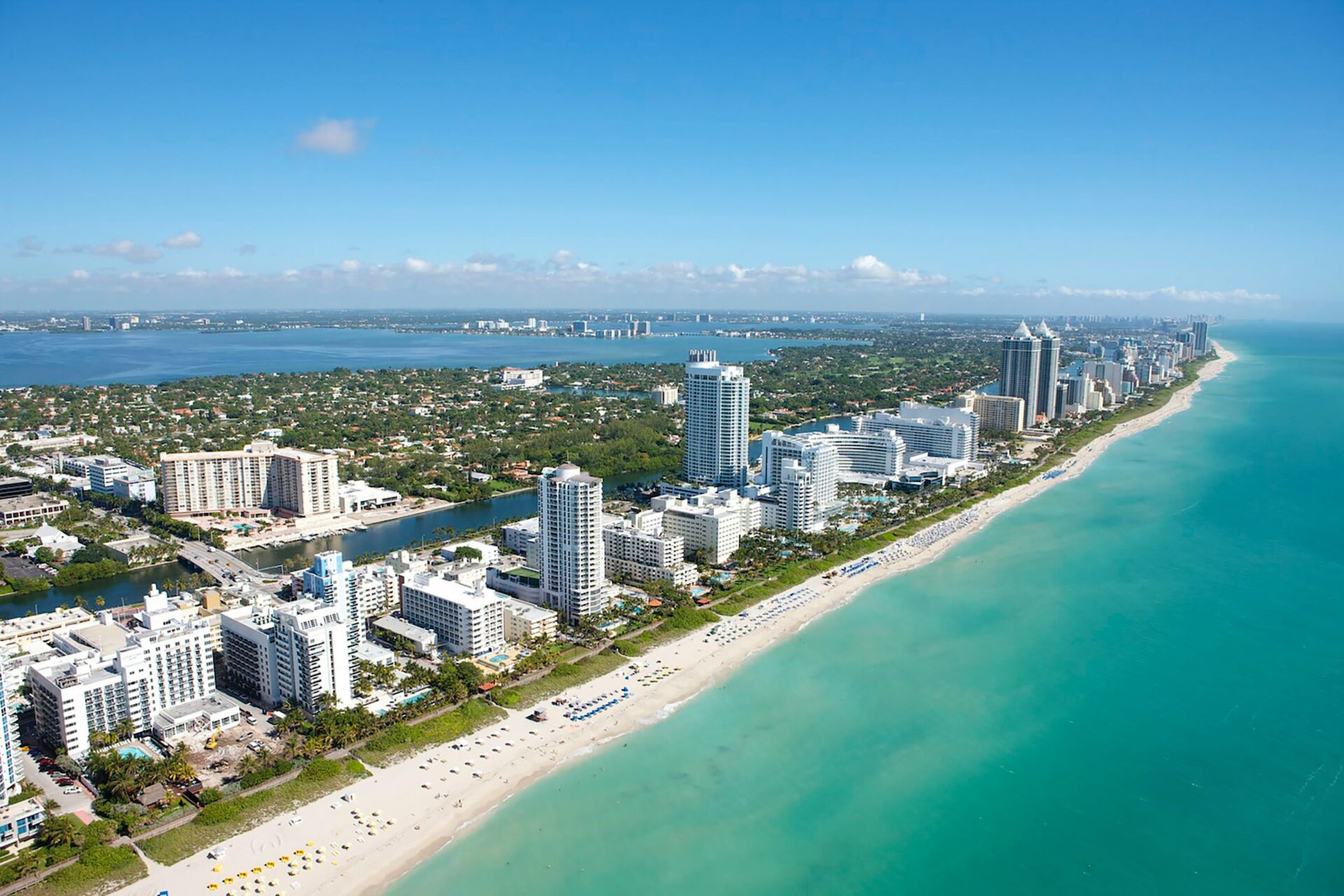 Aerial view of downtown Miami with high-rise buildings, Biscayne Bay, and scattered clouds