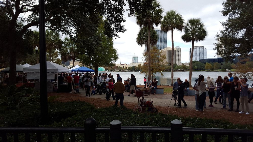 Locals and visitors exploring a busy farmers market in Orlando on a sunny day.