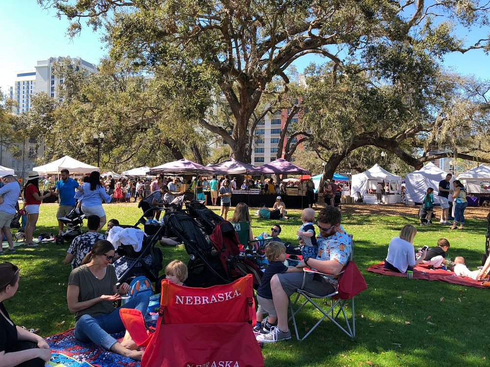 Shoppers browsing fresh produce and local goods at an outdoor farmers market in Orlando