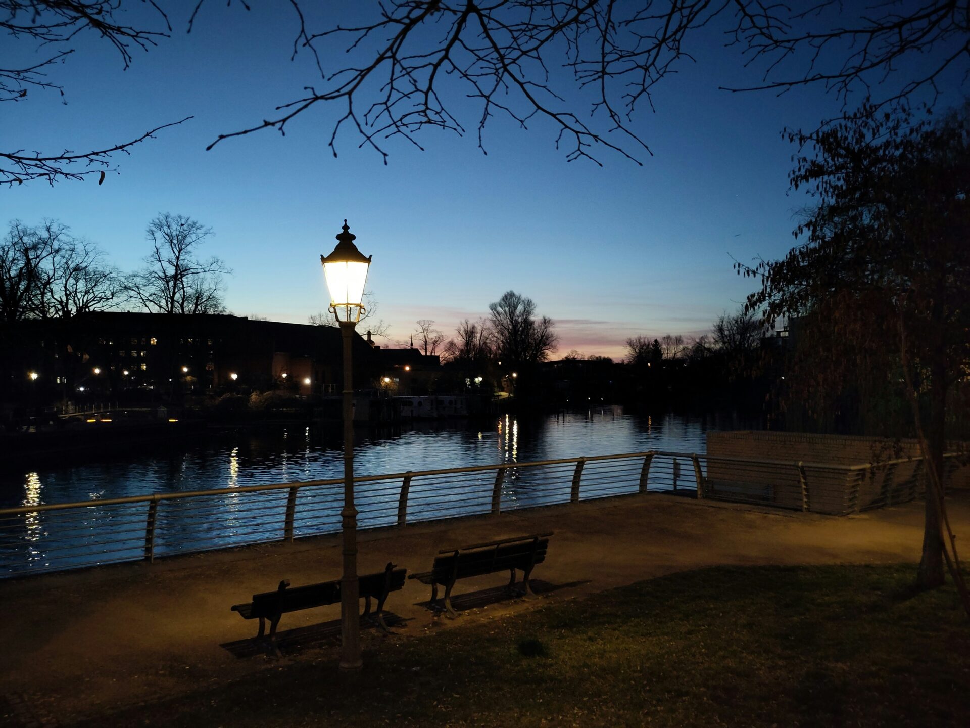 Peaceful evening scene with a glowing lamp in a riverside park in Brandenburg an der Havel