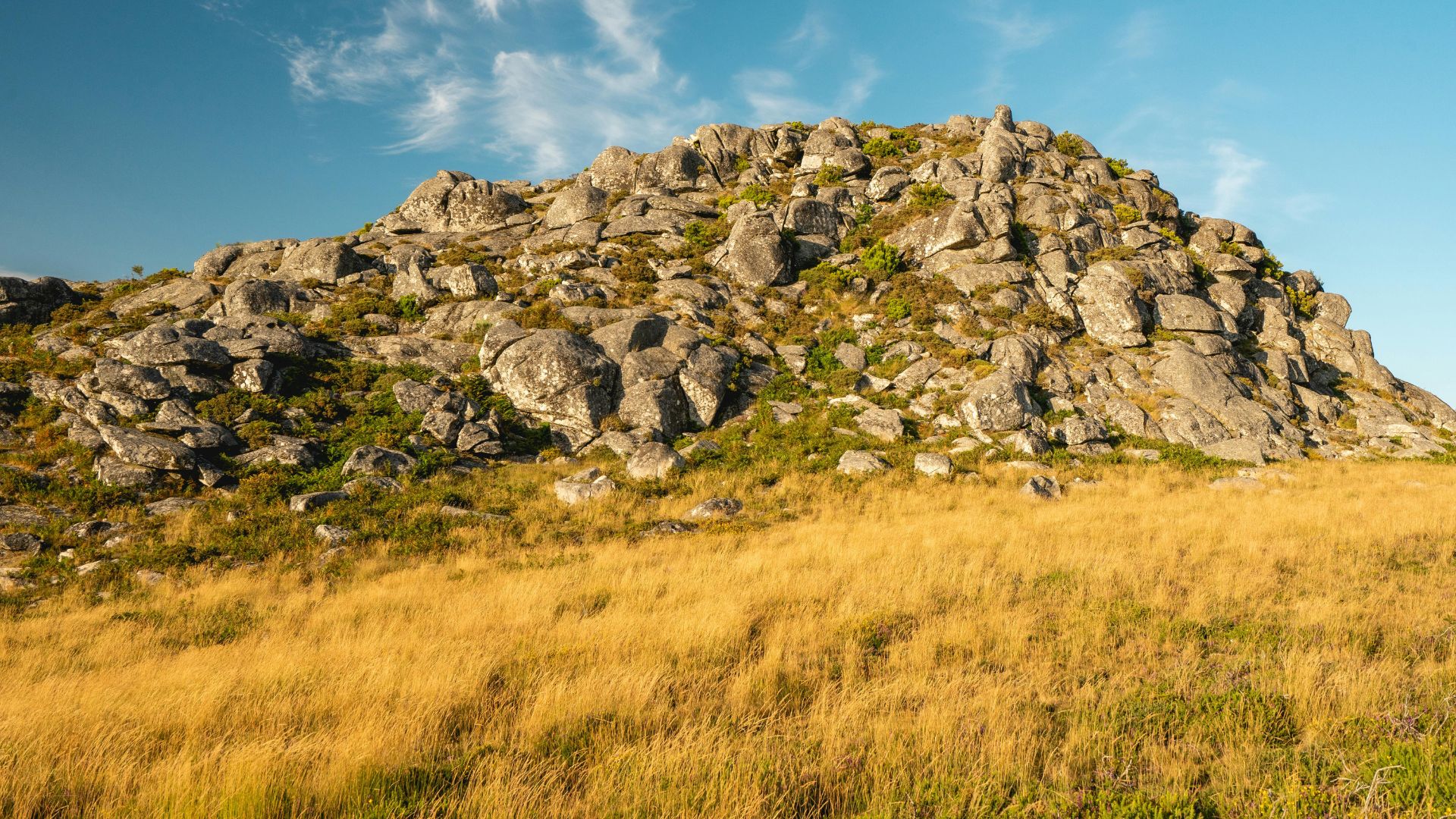 The image shows a rocky, mountainous landscape with grass, characteristic of the Serra da Estrela Natural Park.