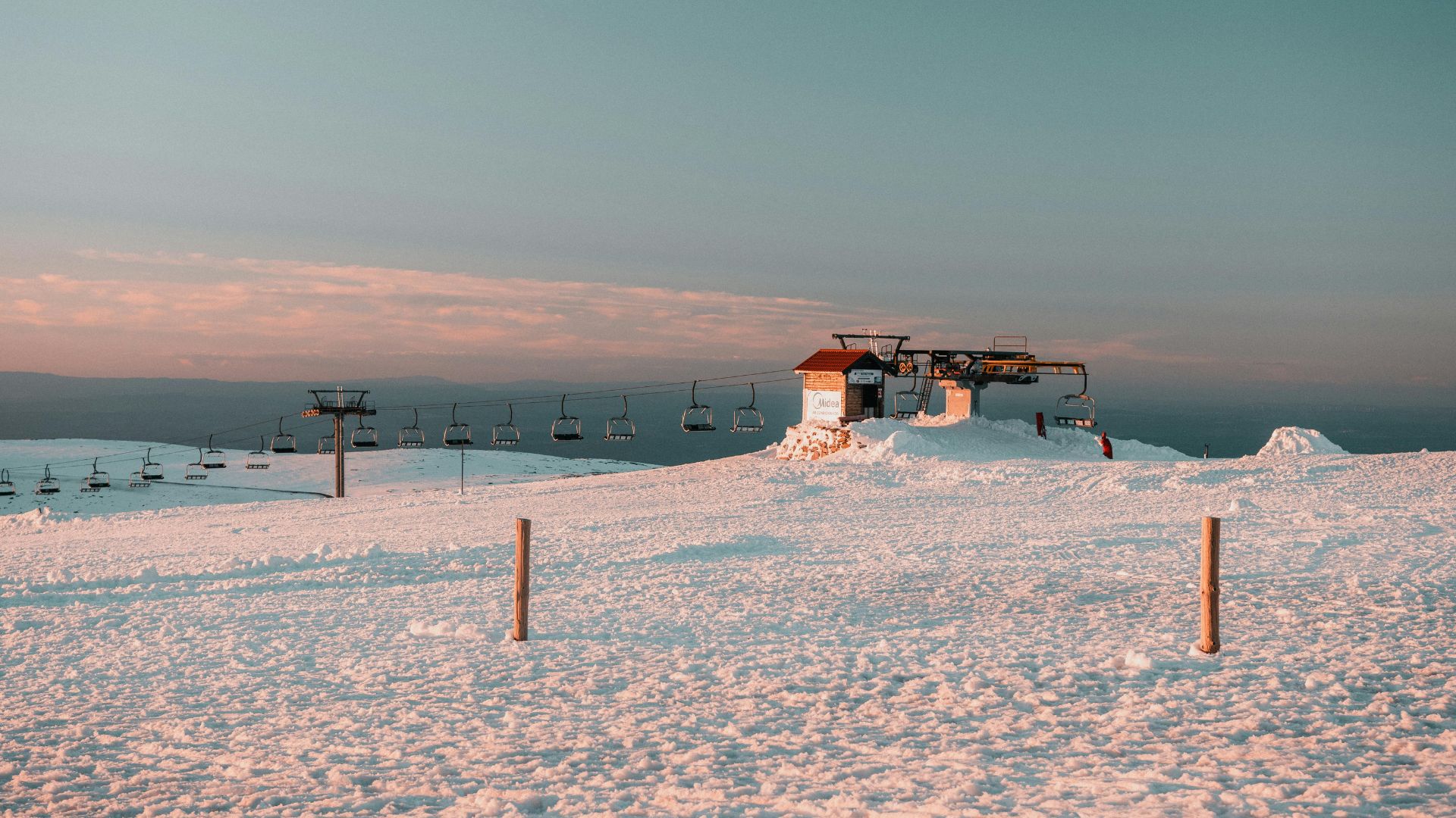 A serene winter scene at the Serra da Estrela ski resort in Central Portugal, featuring snow-covered slopes and ski lifts under a clear sky.