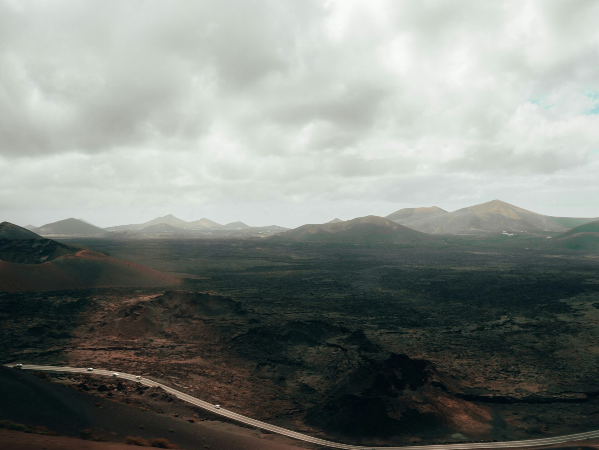 A winding road cutting through the dark volcanic landscape of Timanfaya National Park