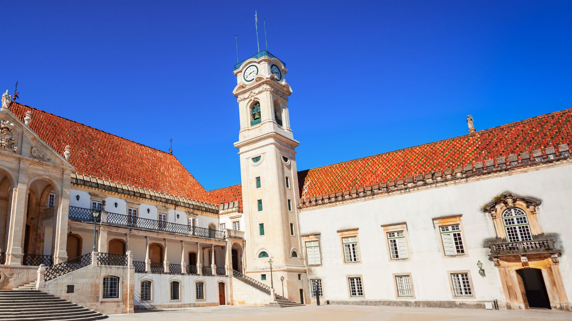This image captures the iconic Tower of the University of Coimbra, a symbol of both the historic university and the city of Coimbra in Central Portugal, set against a clear blue sky. 