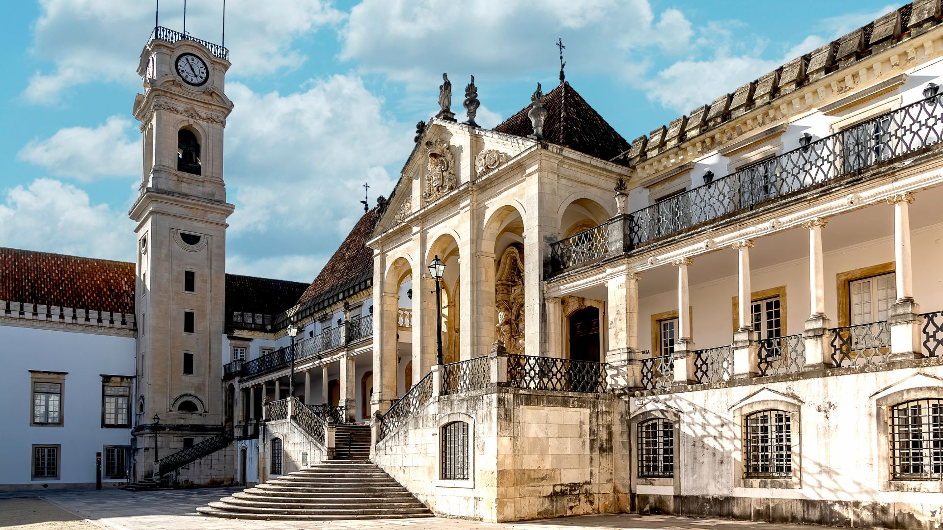 A grand, historic building with a prominent clock tower and ornate architecture, representing the University of Coimbra in Portugal.