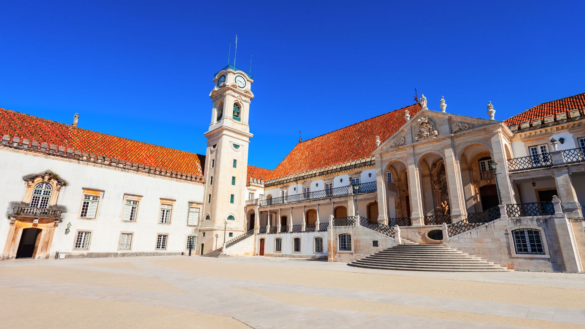 A grand, historic building with a prominent clock tower and ornate architecture, representing the University of Coimbra in Portugal.
