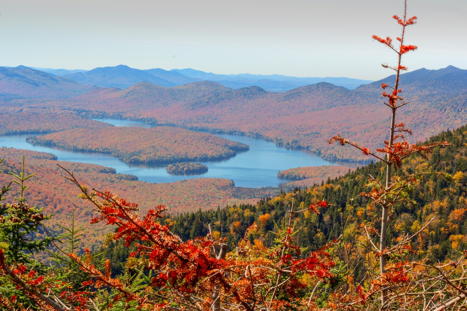 Colorful autumn trees reflecting in a calm lake surrounded by the Adirondack Mountains