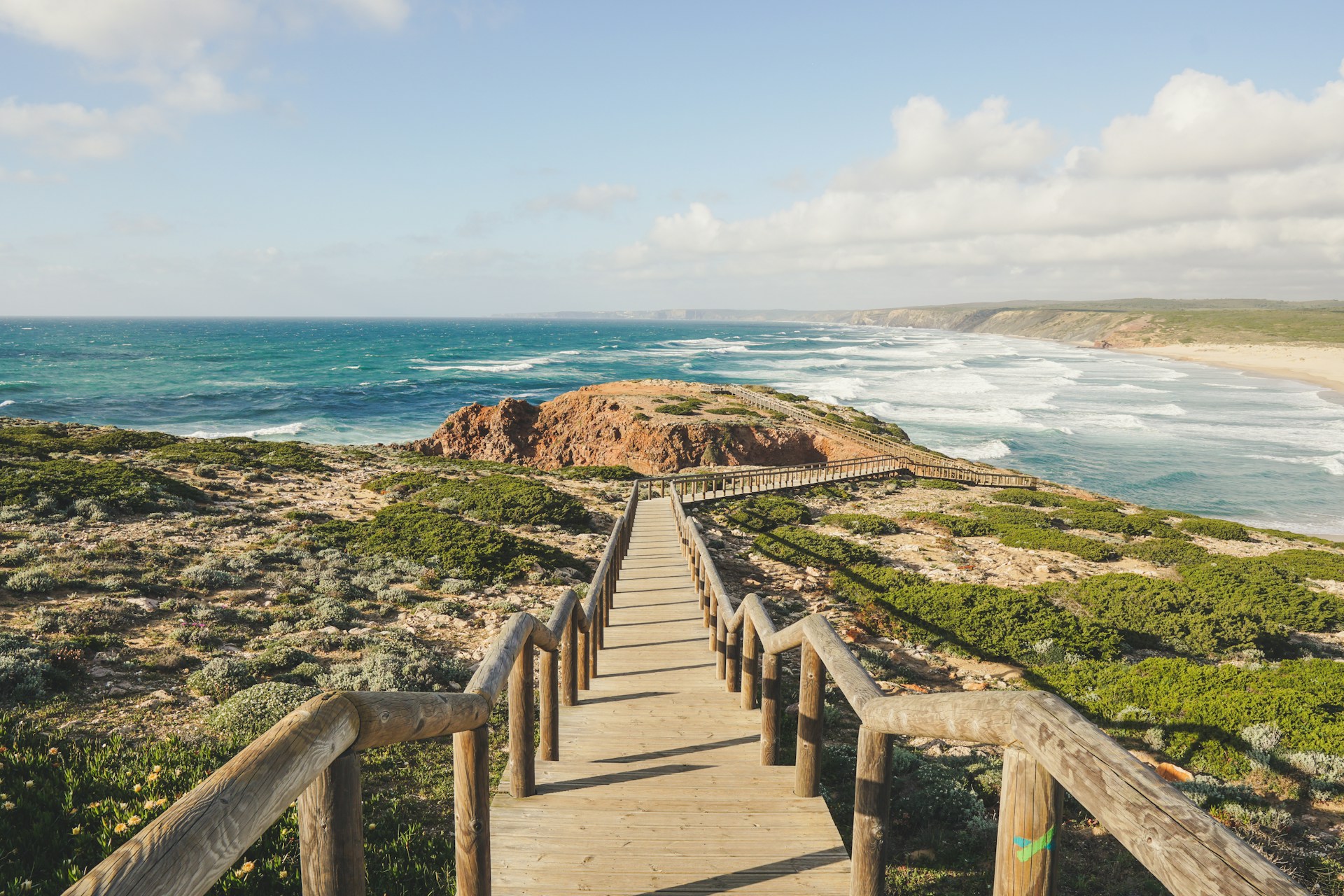 A tranquil Algarve beach with soft waves, warm sand, and natural rock arches typical of southern Portugal.