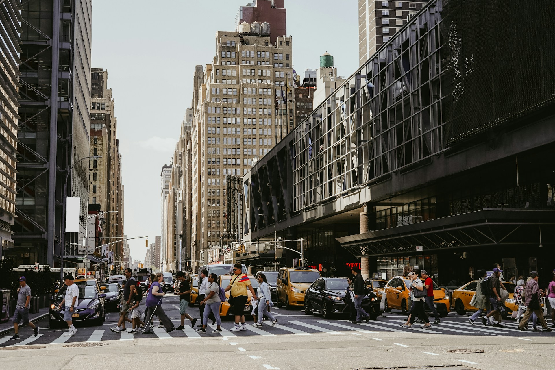 Urban street scene with people crossing a wide pedestrian crosswalk in a busy American city